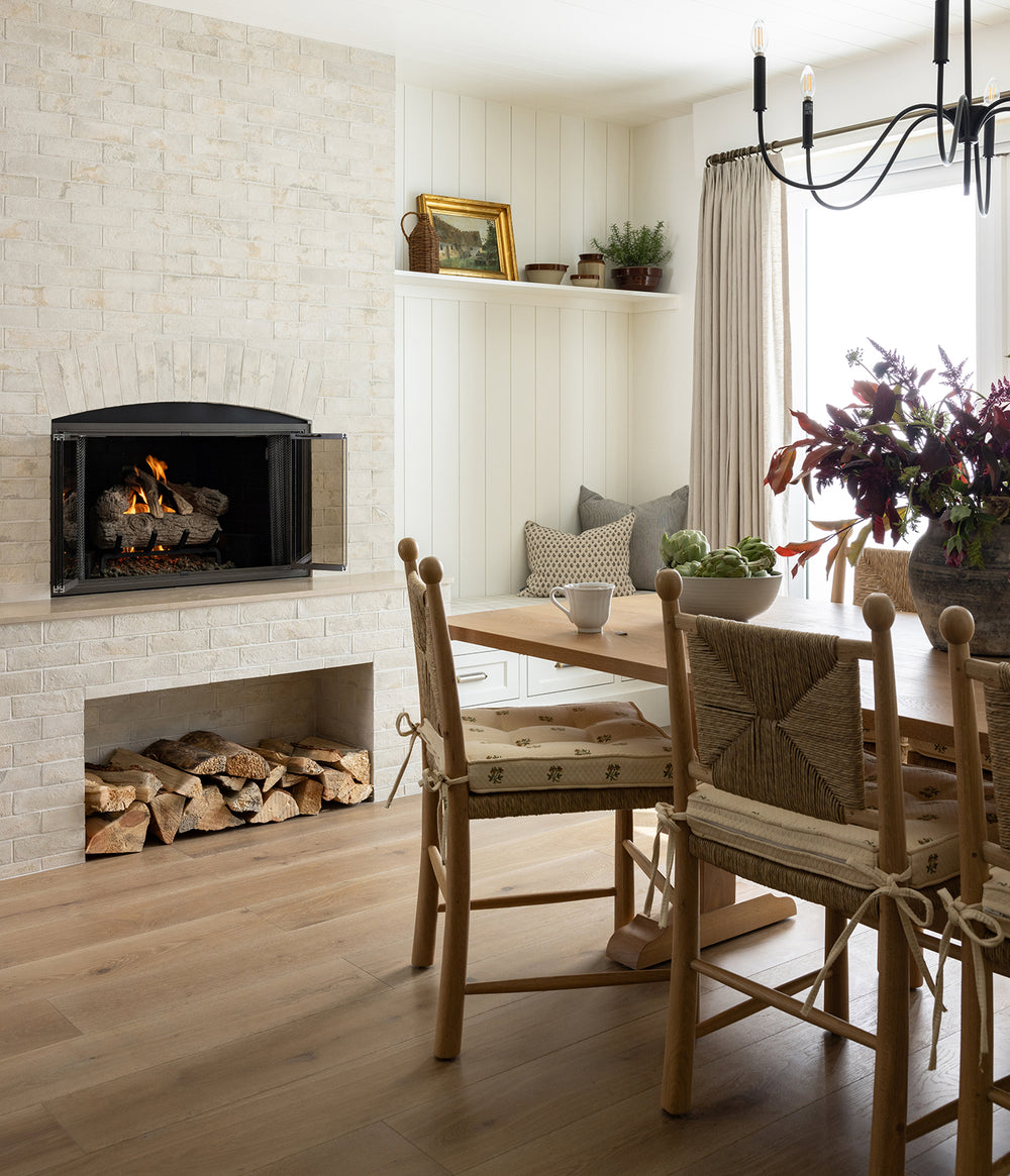Dining room with a fireplace, wooden table, and Olma dining chairs with a custom cushion.