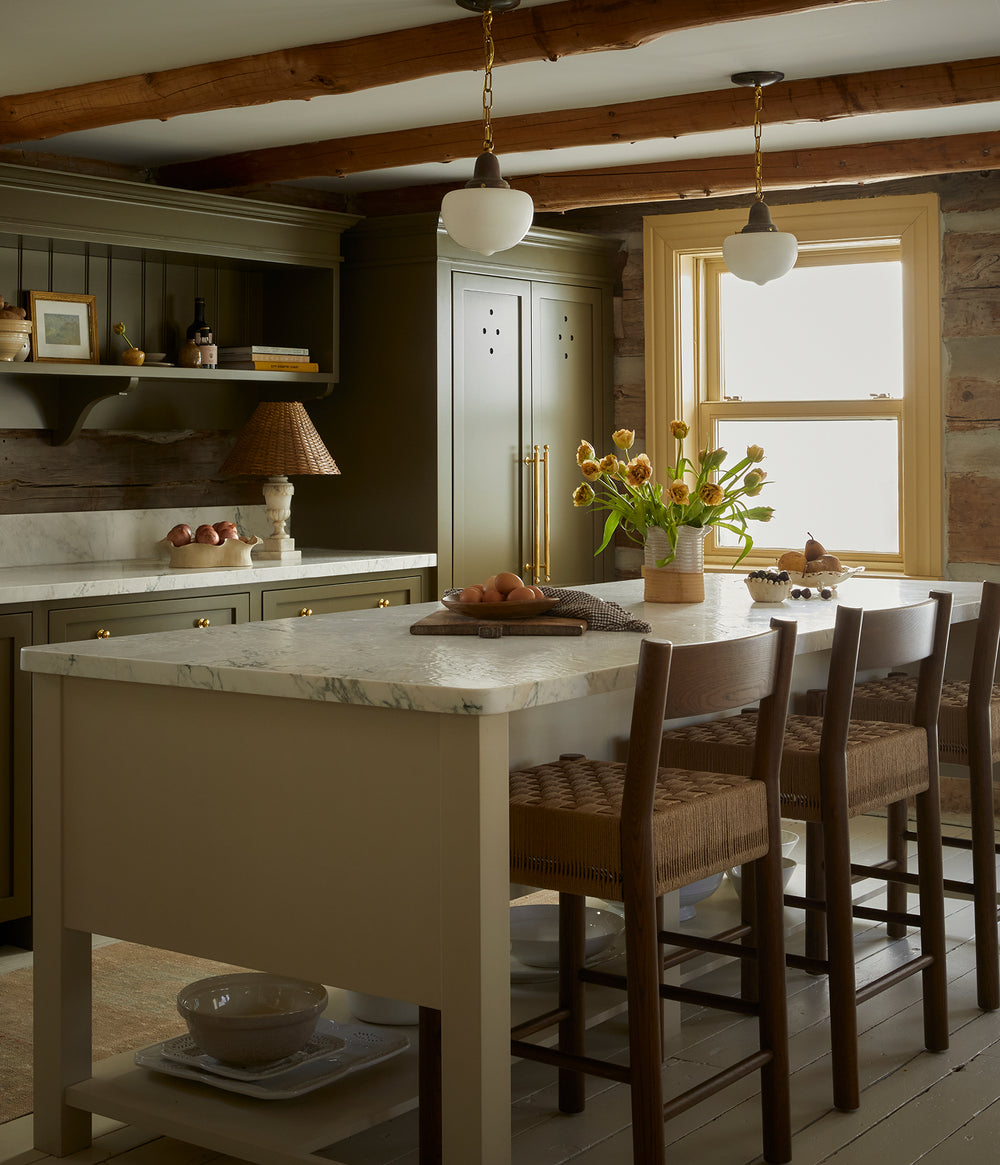 Warm, cozy cottage kitchen with Isa brown oak counter tools at a butter yellow island with a marble counter top.