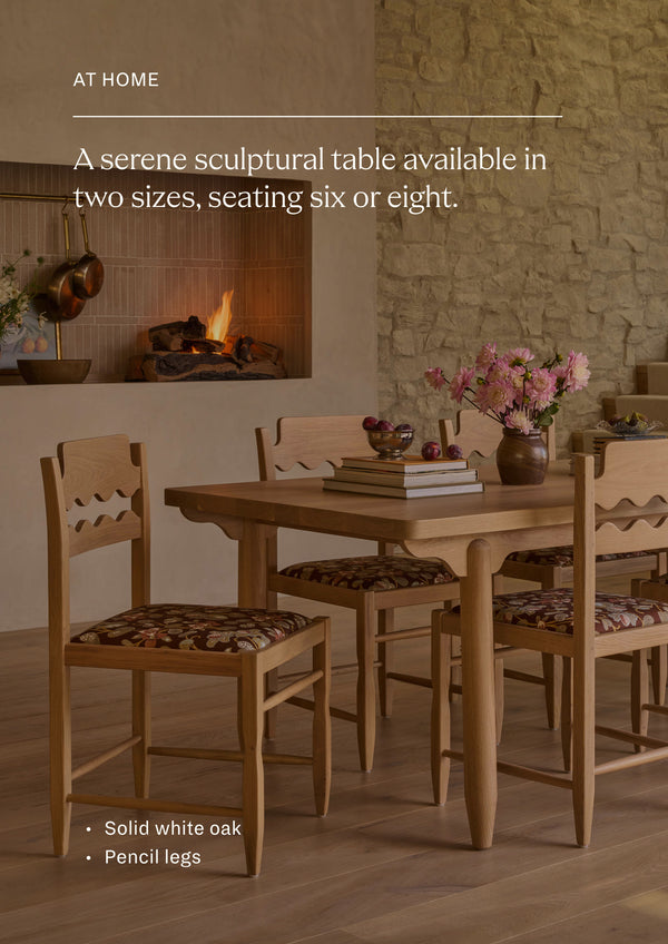 Available in two sizes - seating six or eight. The dining table styled with coordinating dining chairs in a warm, inviting dining room. Surrounded by floral-upholstered seating and set against a stone fireplace, the table creates a welcoming space for gathering and entertaining.