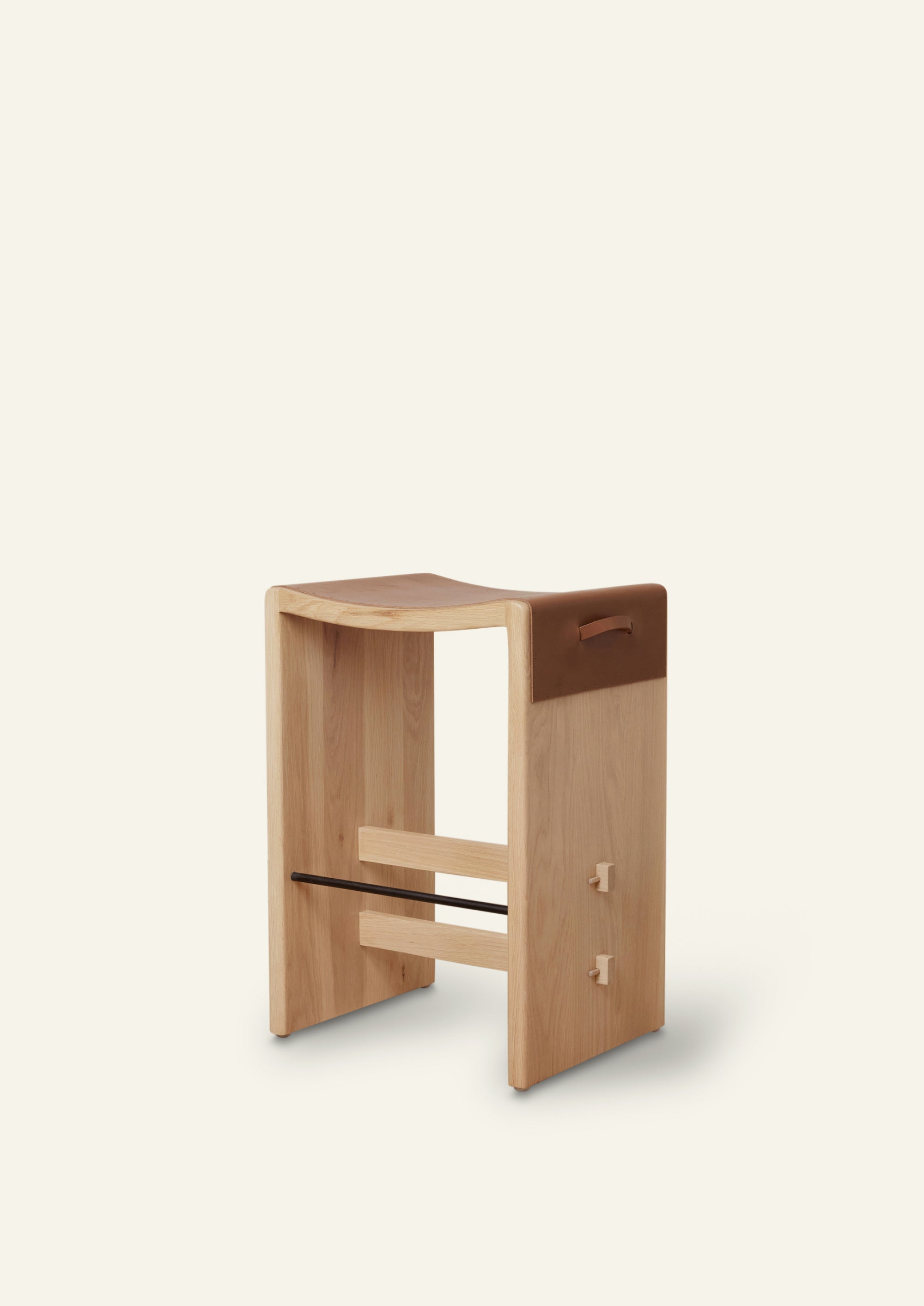 A white oak counter stool with waterfall cognac leather wrapped on the seat. 