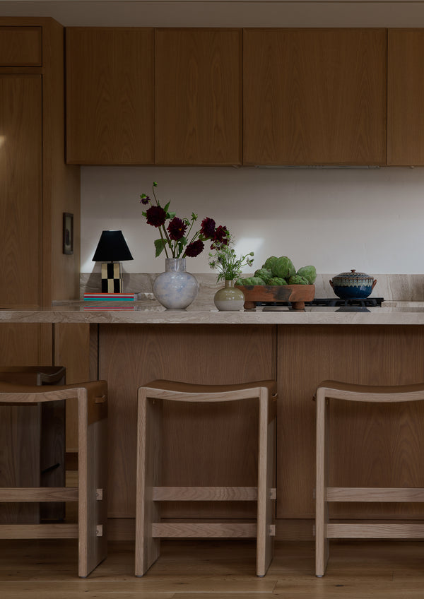 Aya backless counter stool in a modern, warm kitchen with florals and decor. 