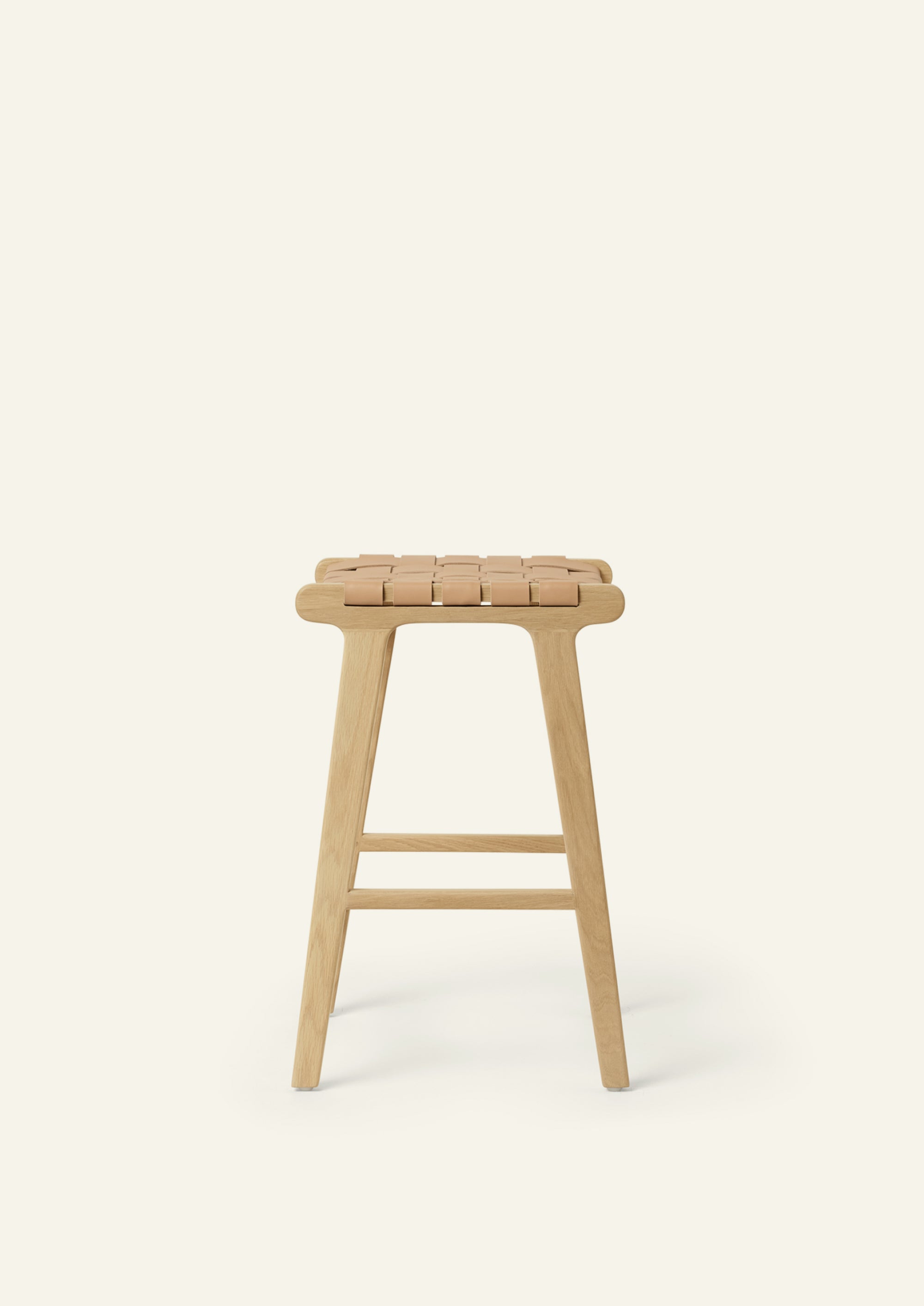 Side view of the Bali Counter Stool in solid white oak with a handwoven leather seat. The sculptural form and woven detailing create a timeless design suited for a variety of interiors.