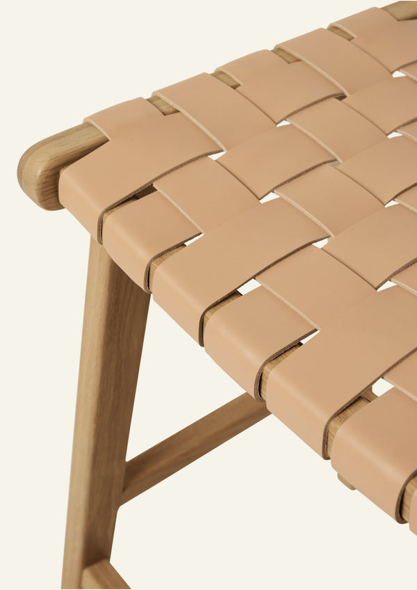 Close-up of the Bali Counter Stool highlighting the handwoven full-grain leather seat. Wide leather straps are woven into a supportive pattern that emphasizes natural texture and artisanal craftsmanship.