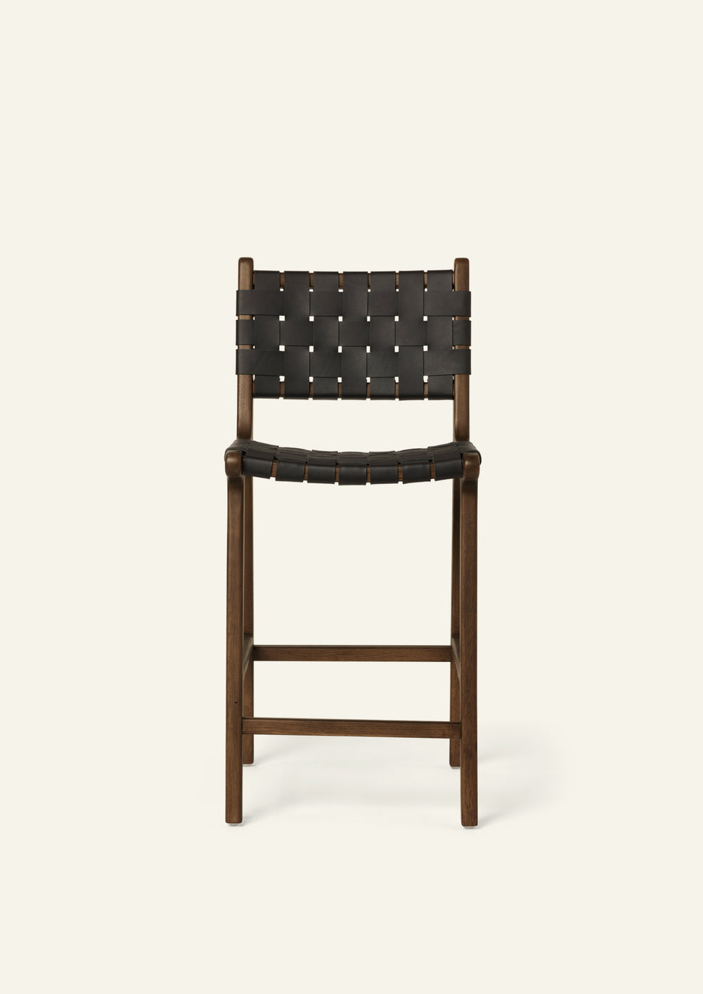 Front view of the Bali Counter Stool in solid brown oak with handwoven black leather, shown in a three-quarter view.