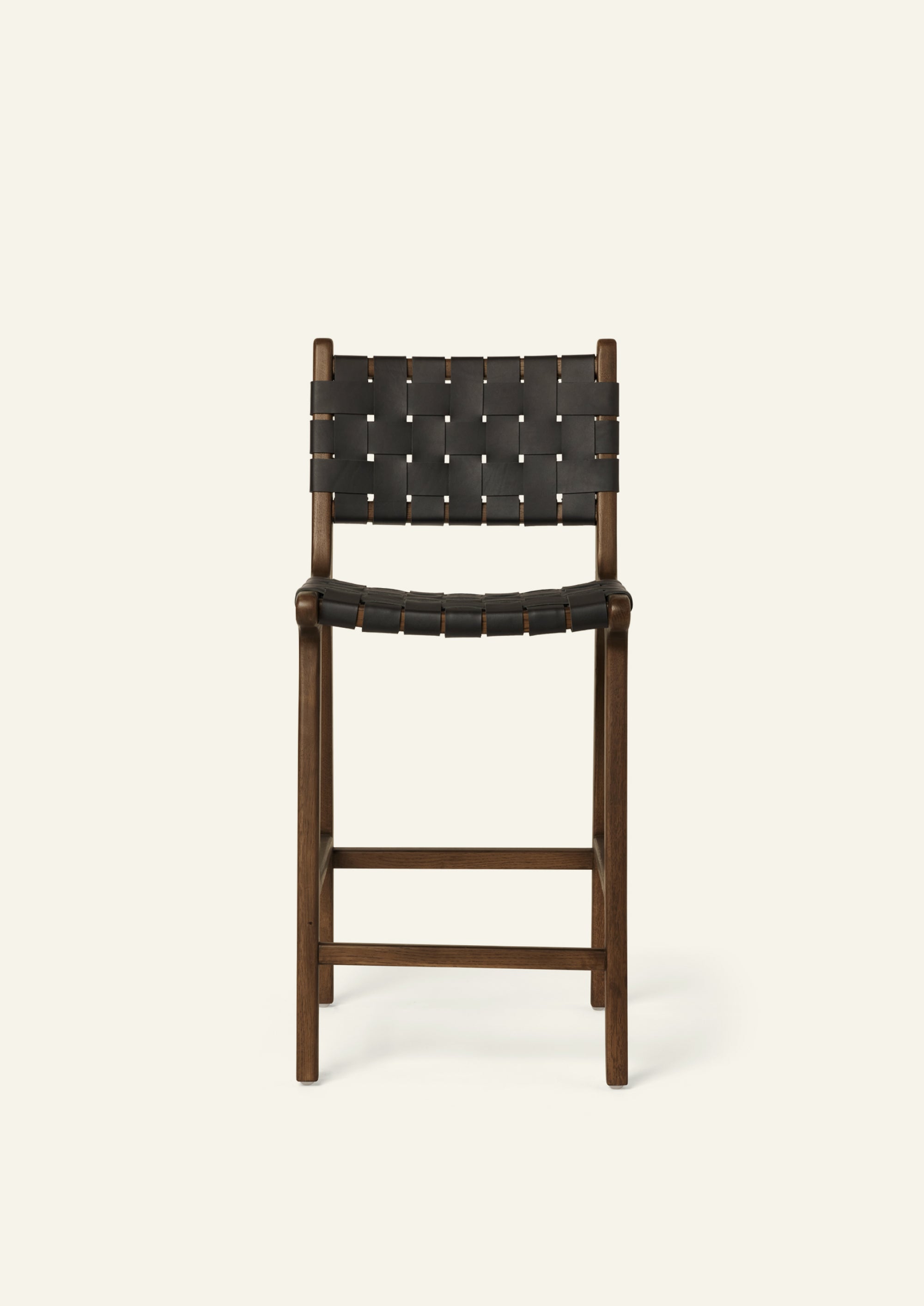 Front view of the Bali Counter Stool in solid brown oak with handwoven black leather, shown in a three-quarter view.