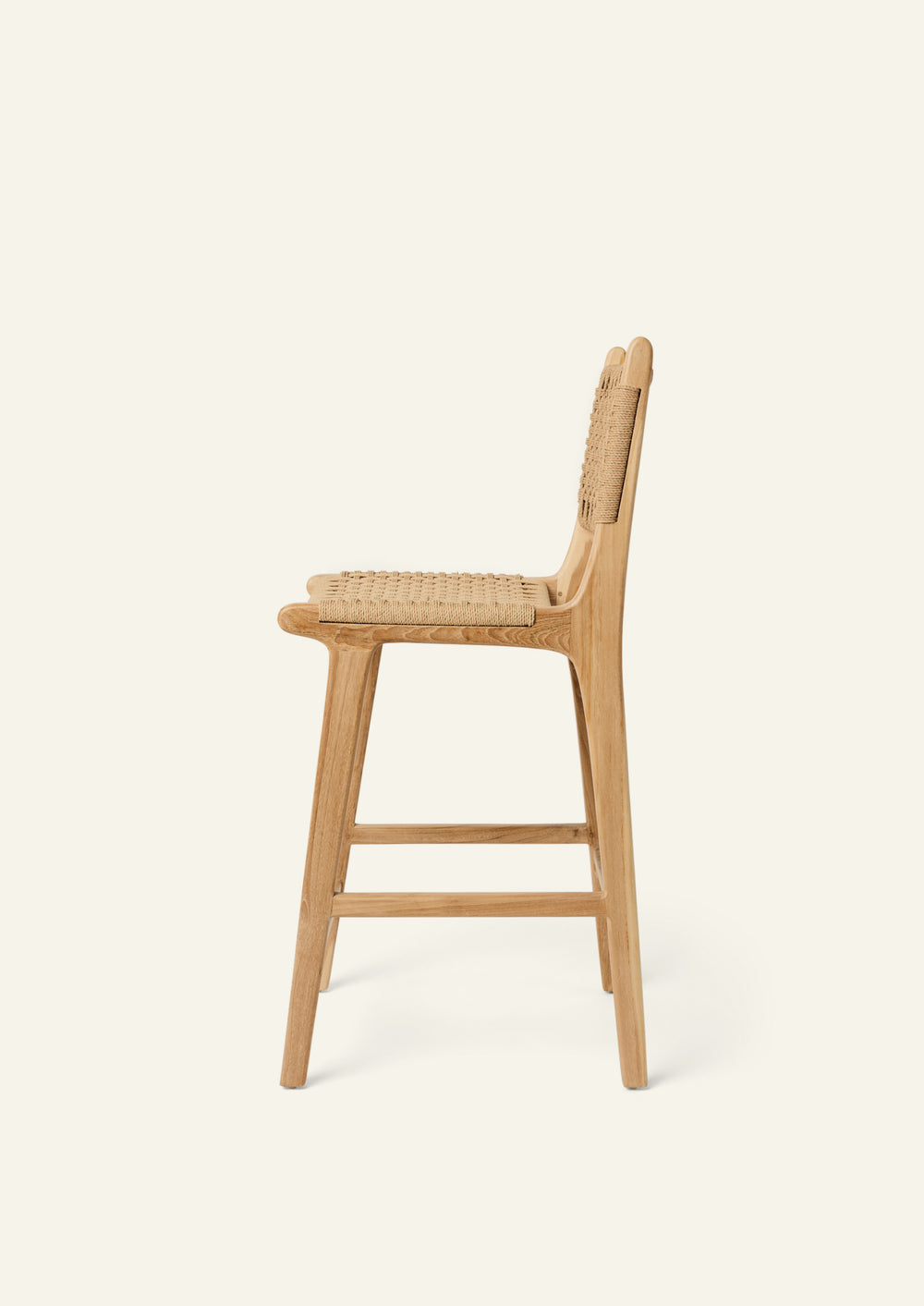 Side profile of the Bali Counter Stool crafted from solid high-grade teak with a handwoven paper cord seat and back. The gently curved frame and woven texture create a relaxed silhouette suited for indoor and outdoor dining.