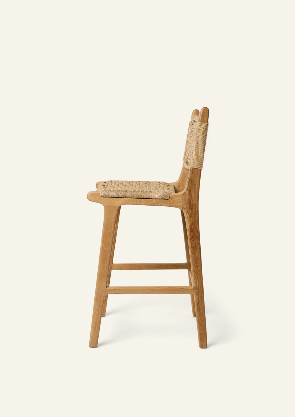 Side profile of the Bali Counter Stool crafted from solid high-grade teak with a handwoven synthetic paper cord seat and back. The gently curved frame and woven texture create a relaxed silhouette suited for indoor and outdoor dining.
