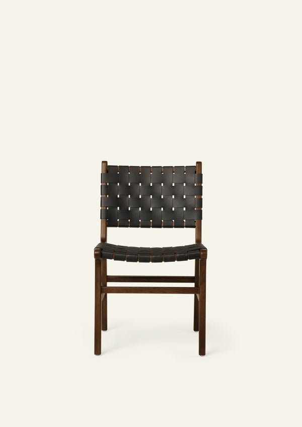 Front view of the Bali Dining Chair featuring woven black full-grain leather straps across the seat and backrest. The rich black leather creates a bold, graphic contrast against the warm brown oak frame.