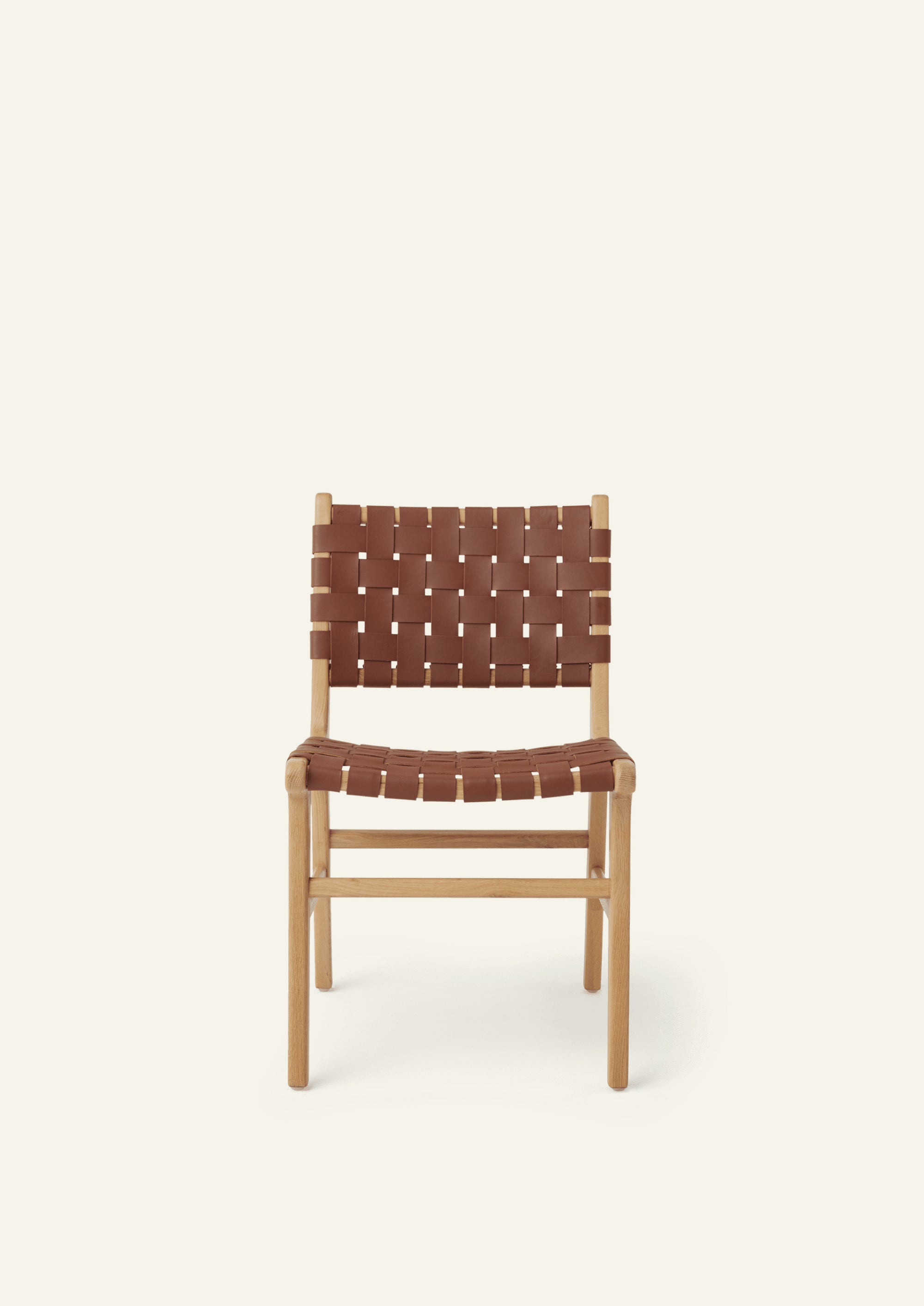 Front view of the Bali Dining Chair with a woven whiskey leather seat and back. Rounded edges, softly tapered legs, and natural materials create a warm and inviting presence.