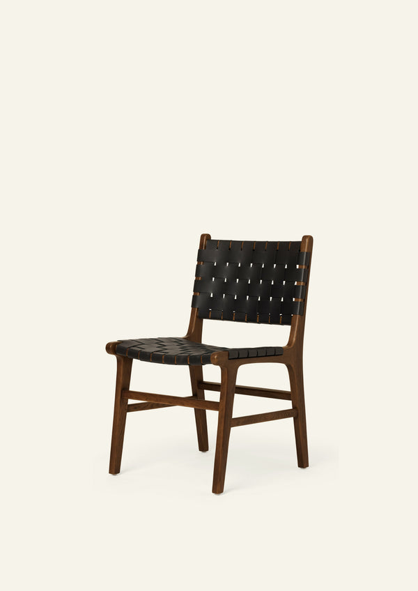 Angled view of the Bali Dining Chair with woven black full-grain leather seating and backrest. The combination of dark leather and warm oak creates a refined, contemporary look.