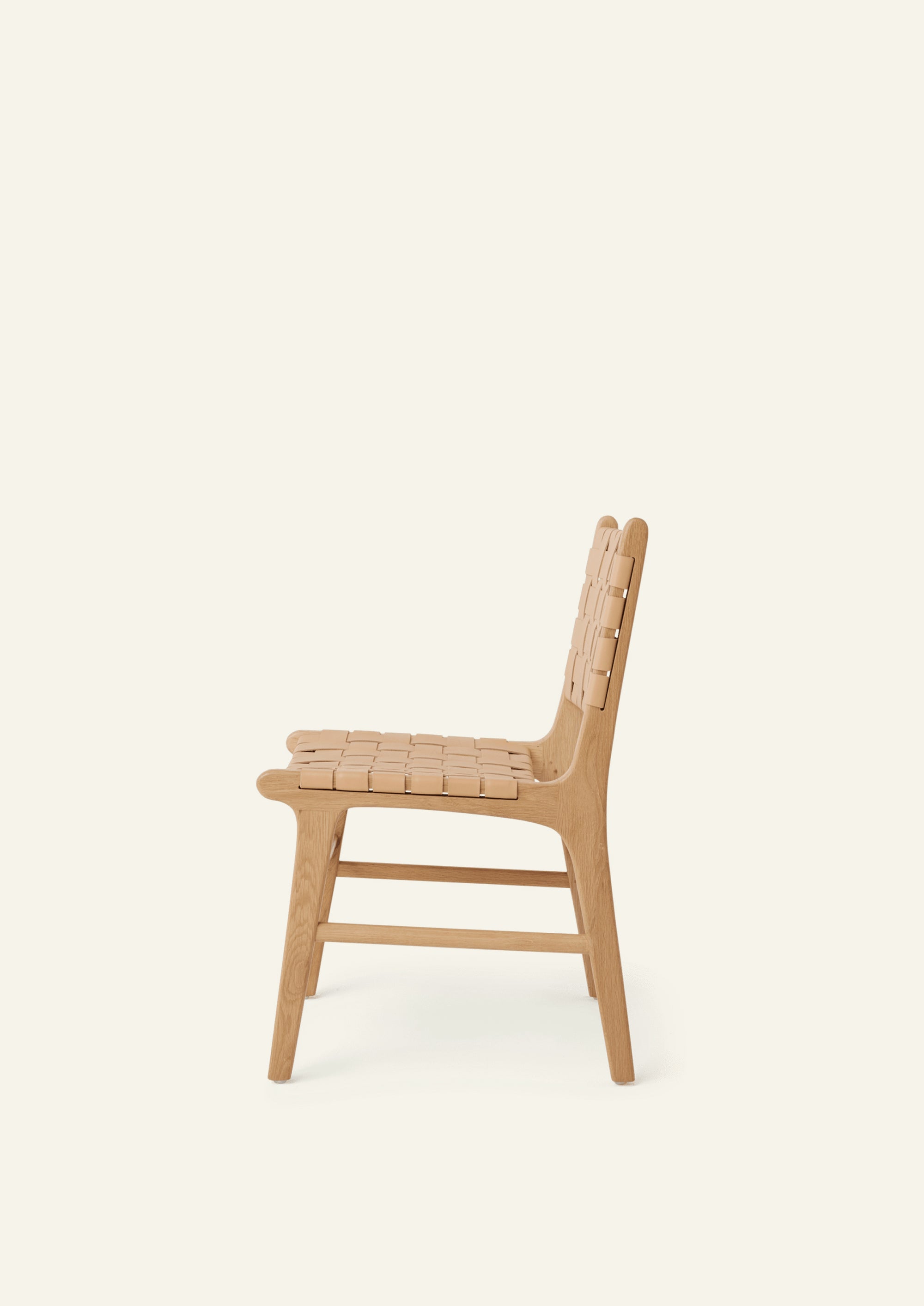 Side profile of the Bali Dining Chair crafted from solid white oak with a full-grain natural leather seat and back. The gently reclined silhouette and integrated frame create a sculptural, modern form.