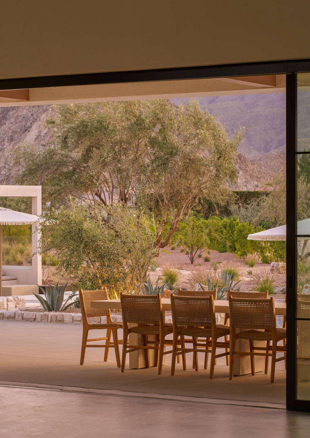 Bali Dining Chairs in outdoor synthetic paper cord styled around a teak dining table on a covered patio overlooking a desert landscape.