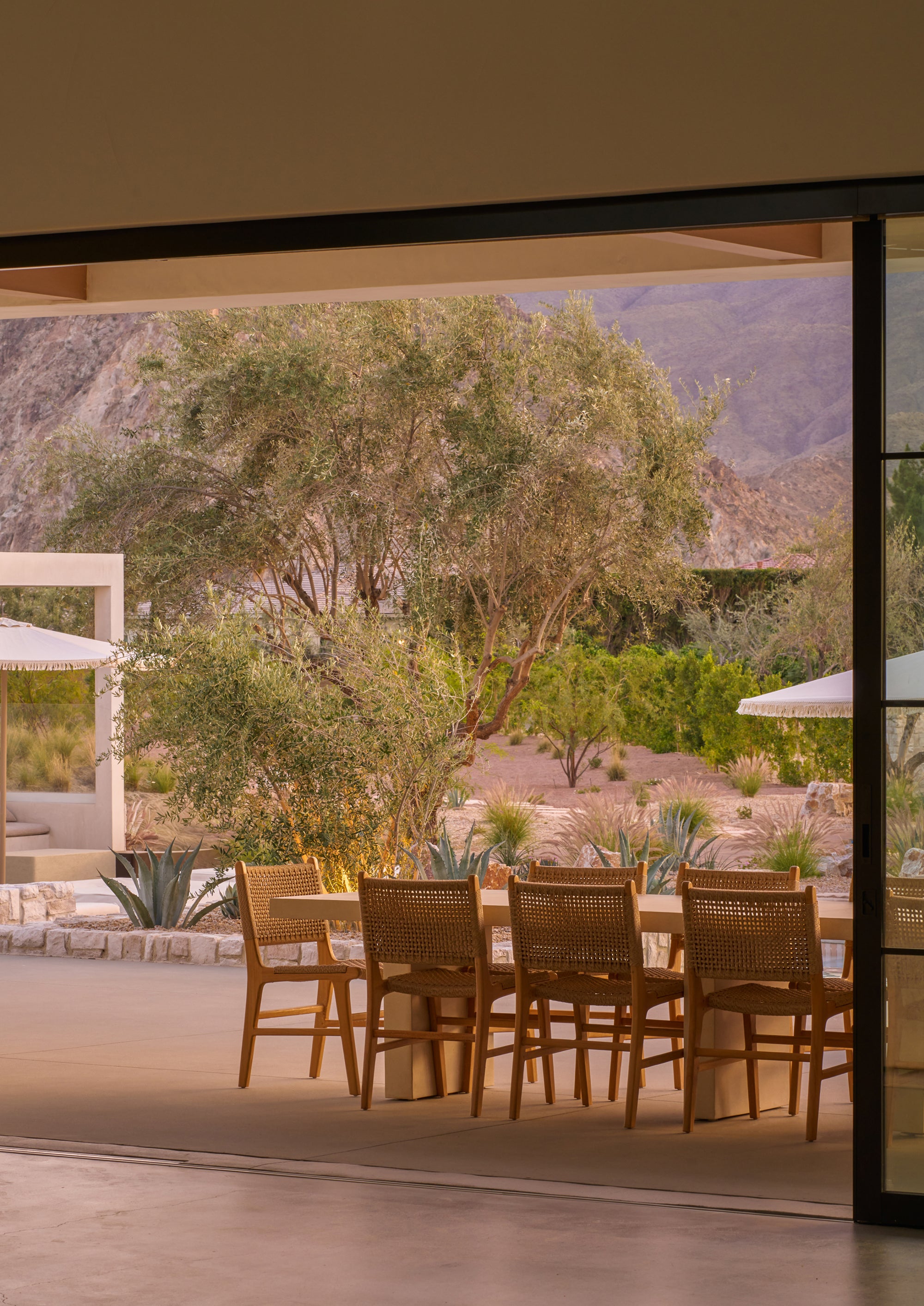 Bali Dining Chairs in outdoor synthetic paper cord styled around a teak dining table on a covered patio overlooking a desert landscape.