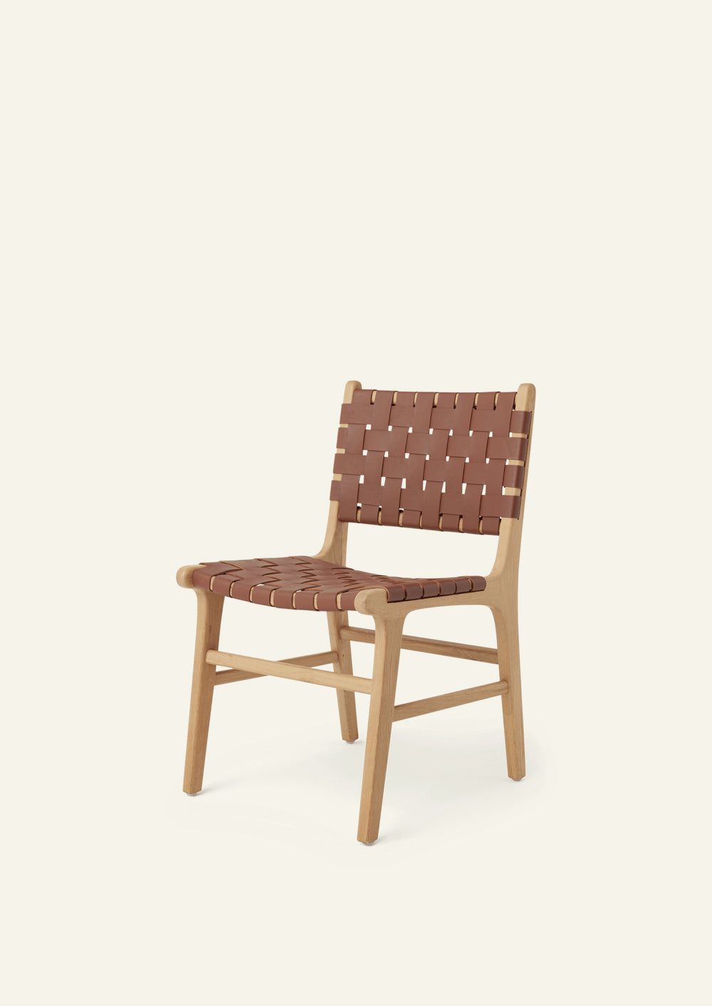 Angled view of the Bali Dining Chair with a woven whiskey leather seat and back. Rounded edges, softly tapered legs, and natural materials create a warm and inviting presence.