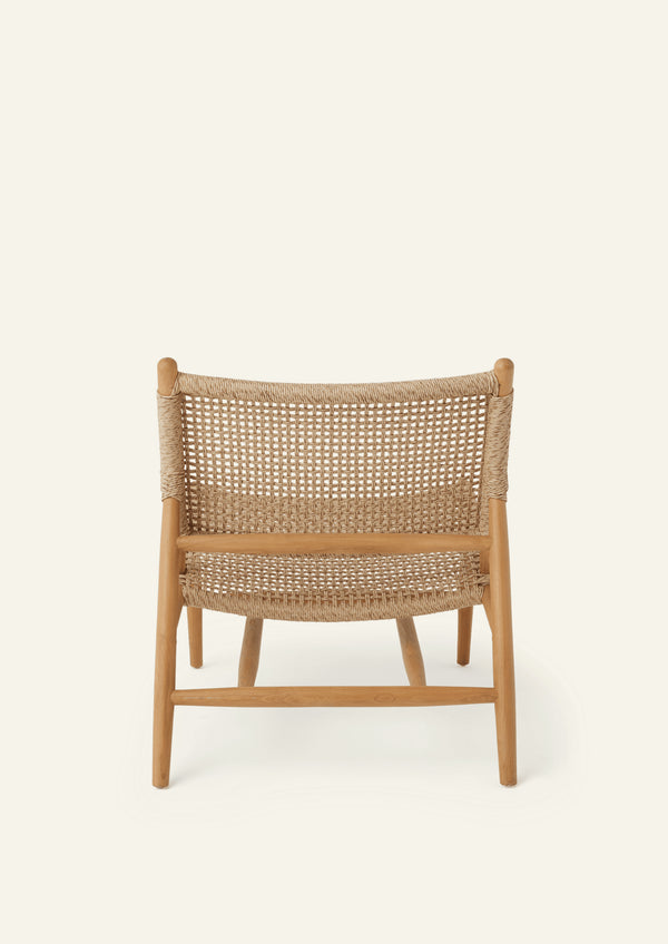 Rear view of the lounge chair featuring a woven backrest suspended within a solid teak frame. The clean geometry and woven texture create a balance of support, comfort, and visual lightness.