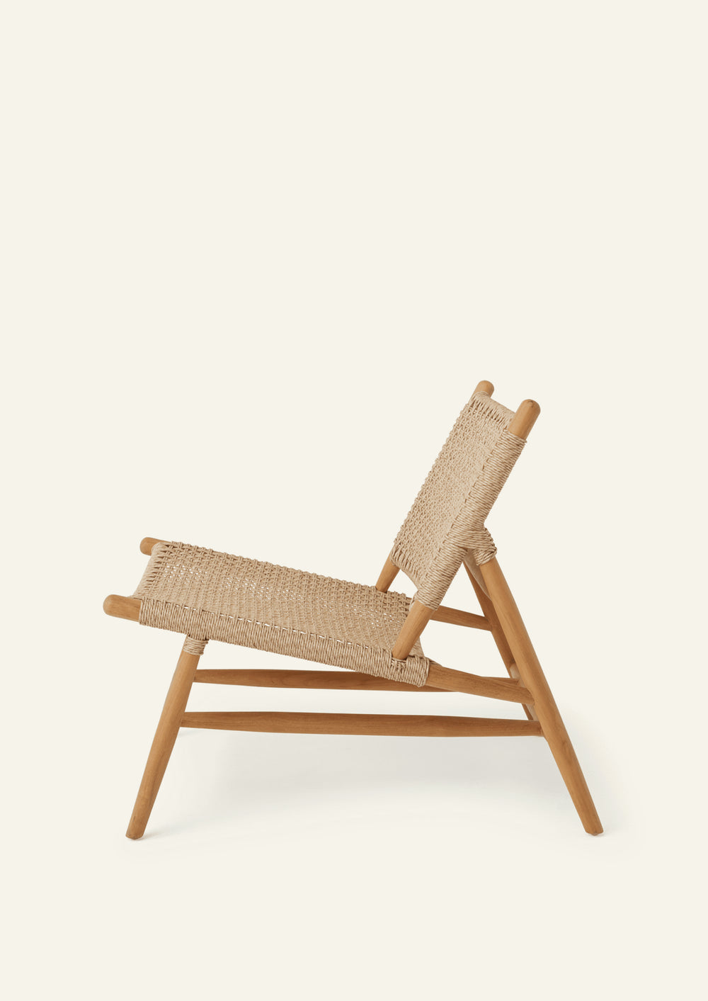Side profile of the lounge chair highlighting its low-slung seat, reclined woven backrest, and angled teak frame. The relaxed proportions are designed for comfortable lounging indoors or outdoors.