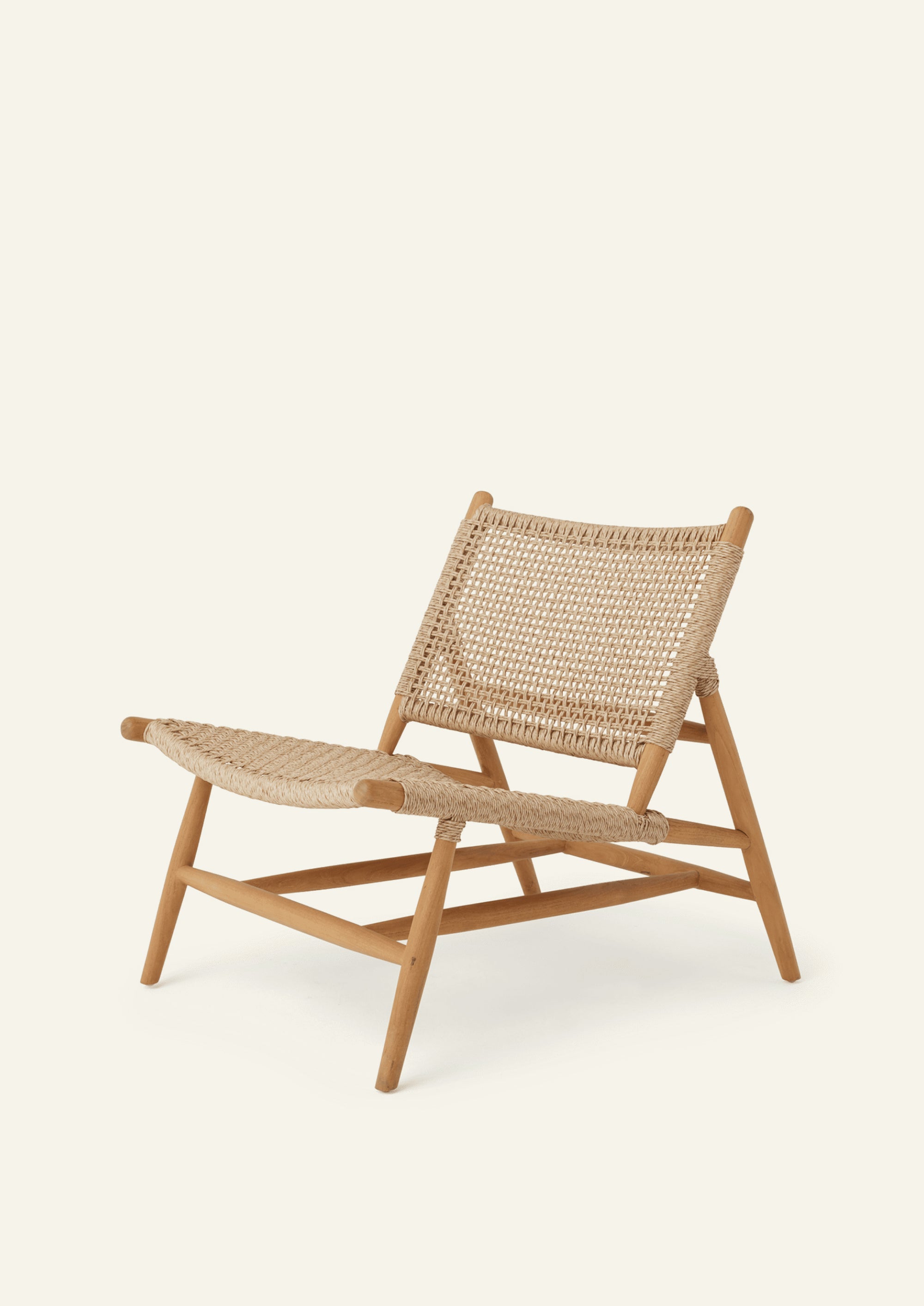 Three-quarter view of a low-profile lounge chair crafted from solid teak and woven synthetic paper cord. The reclined silhouette, airy woven seat, and open-frame construction create a relaxed, resort-inspired look designed for indoor and outdoor living.