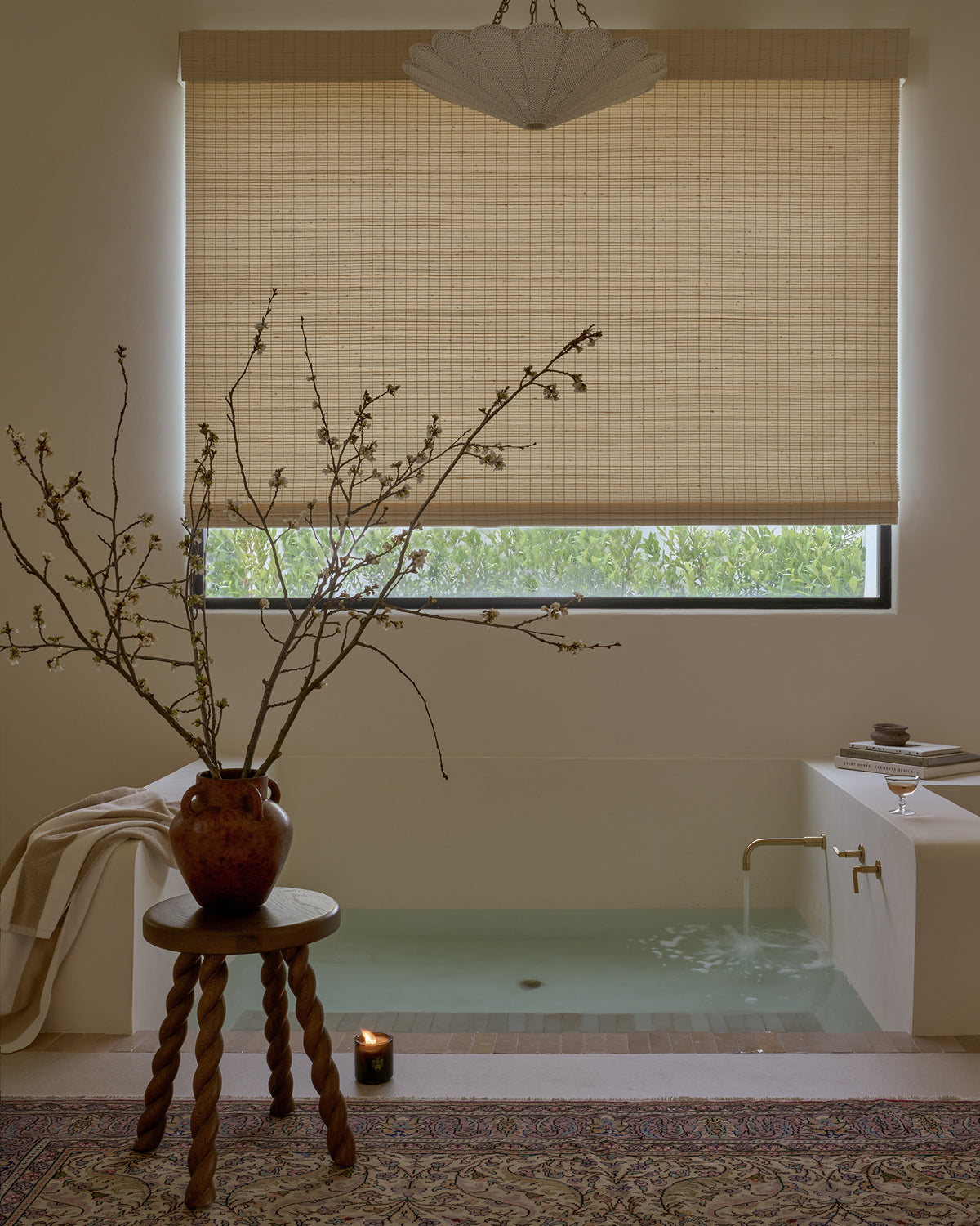 Bathroom with a sunken bathtub, Twist brown oak side table, and decorative vase.