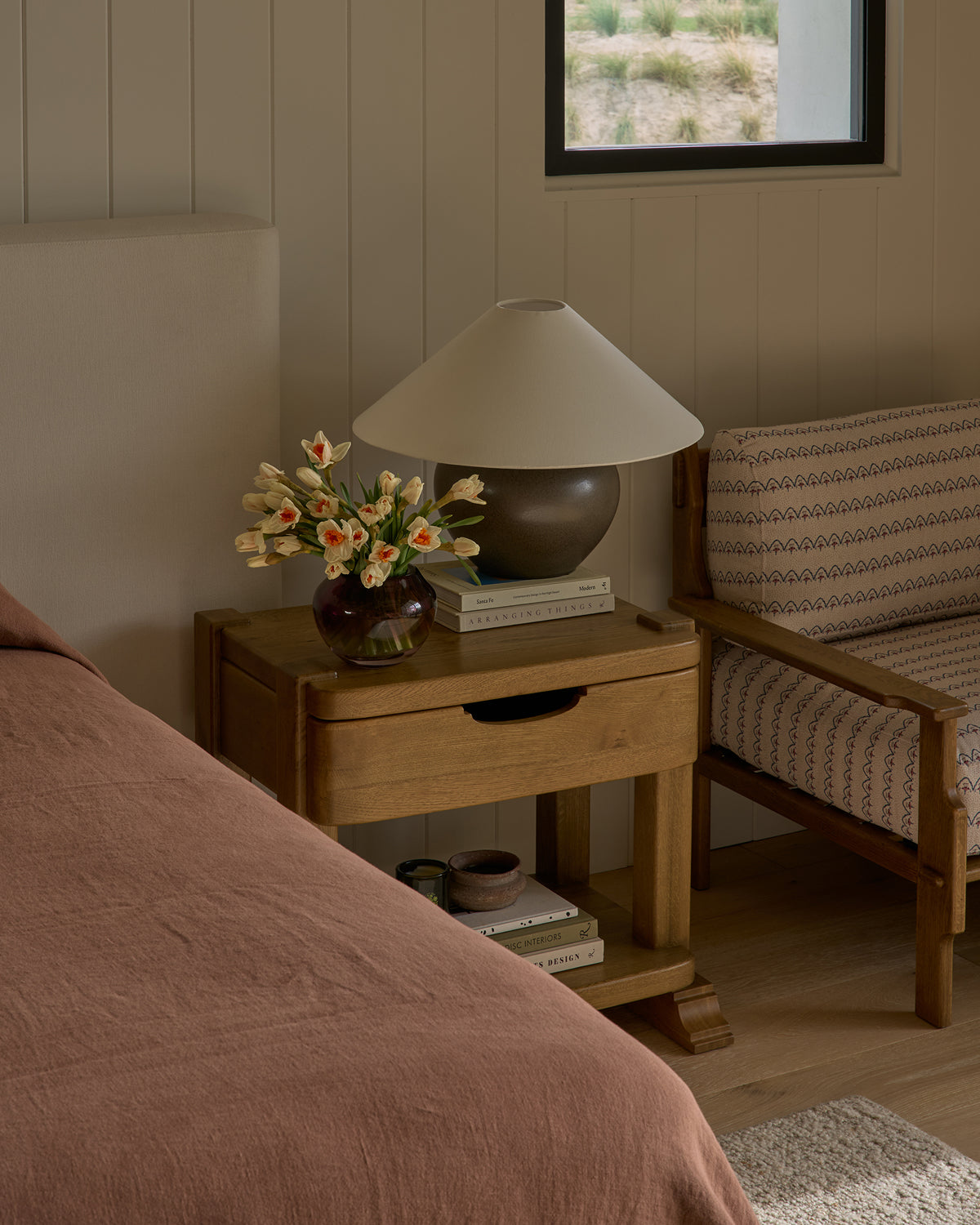 Modern bedroom with Mina honey oak nightstand, lamp, and chair.