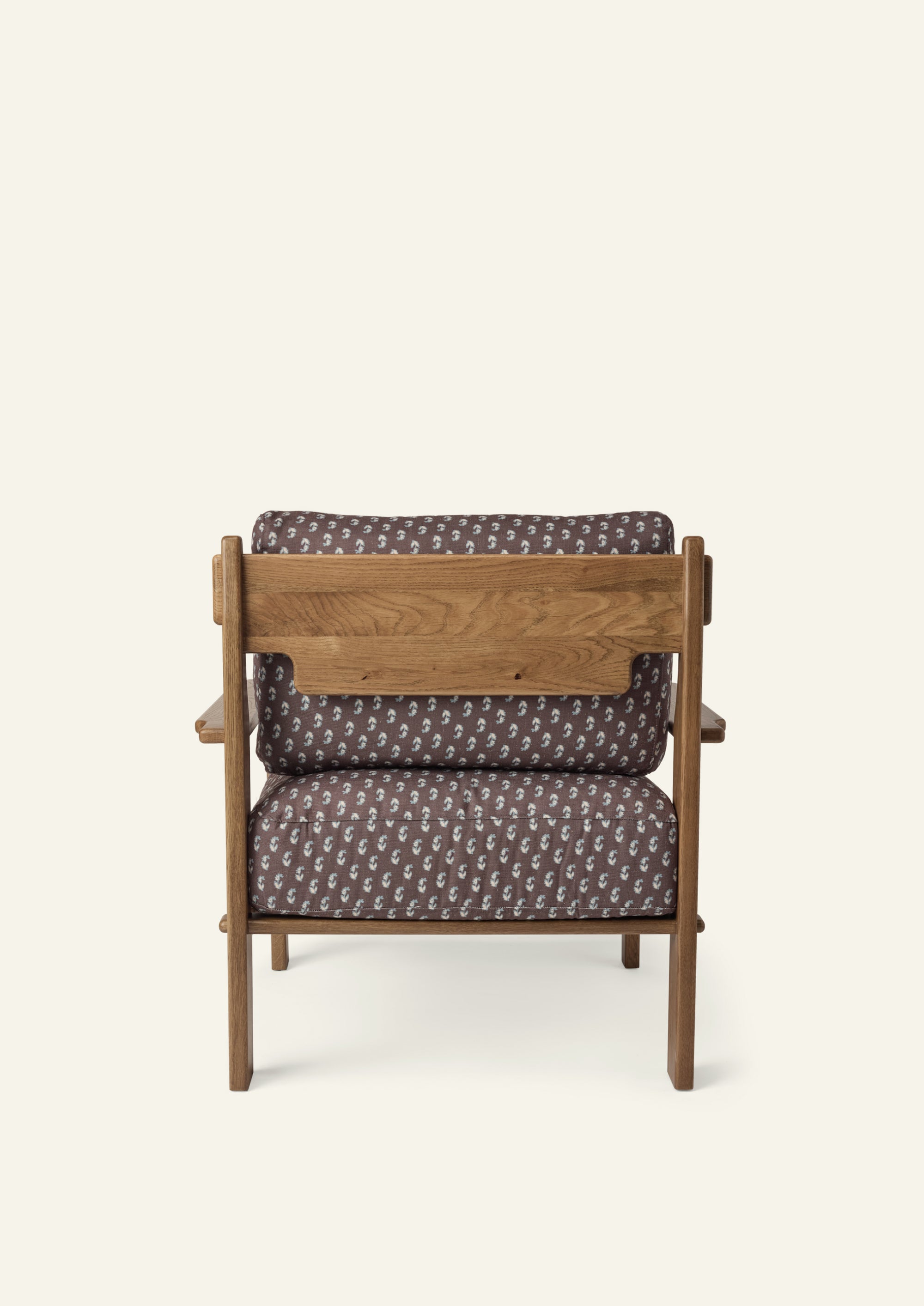 Rear view of the lounge chair showcasing the solid honey oak frame, exposed wood back panel, and Cocoa Floral upholstered cushions. Warm wood grain and thoughtful construction are visible from every angle.