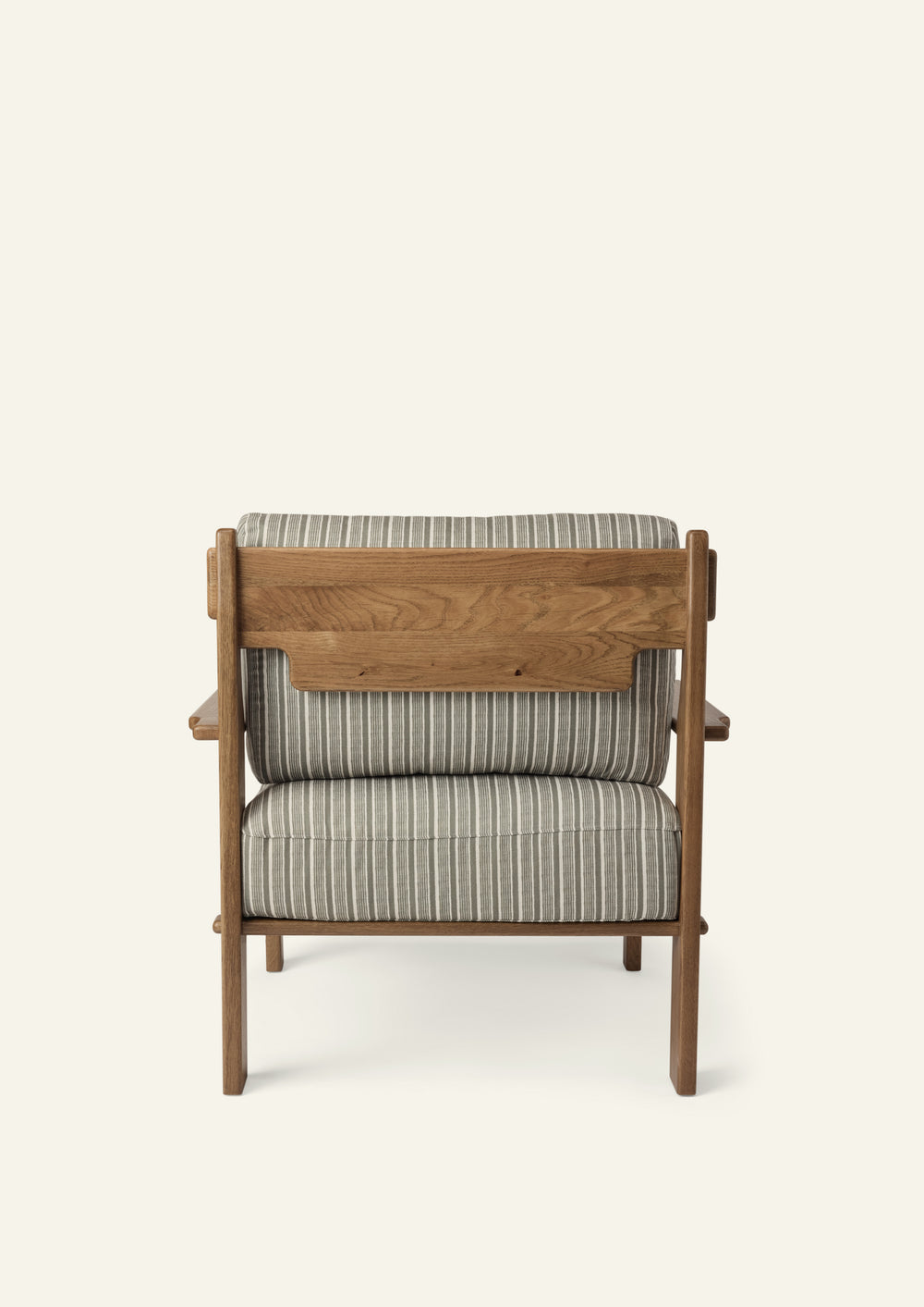 Rear view of the lounge chair showcasing the solid honey oak frame, exposed wood back panel, and Neutral Stripe upholstered cushions. Thoughtful craftsmanship highlights the chair from every angle.