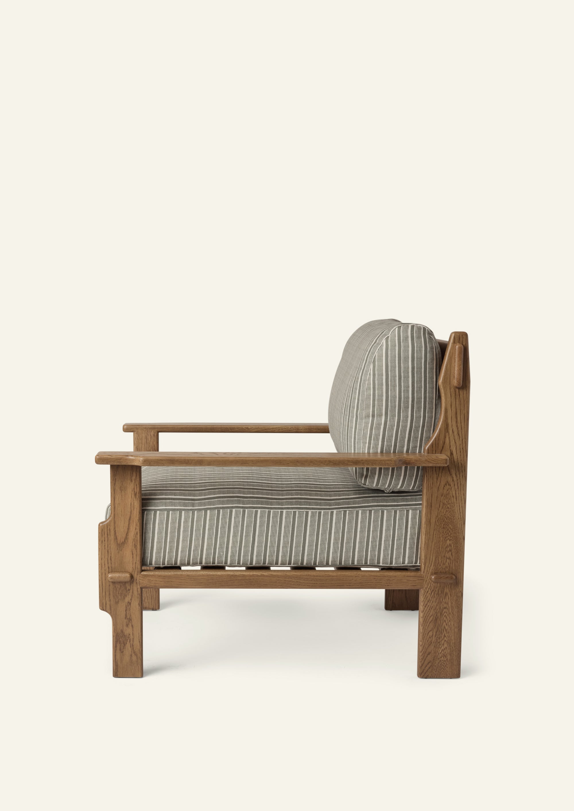 Side profile of the lounge chair highlighting its deep seat cushion, supportive back cushion, and solid honey oak frame. Clean lines and handcrafted details balance comfort with timeless design.
