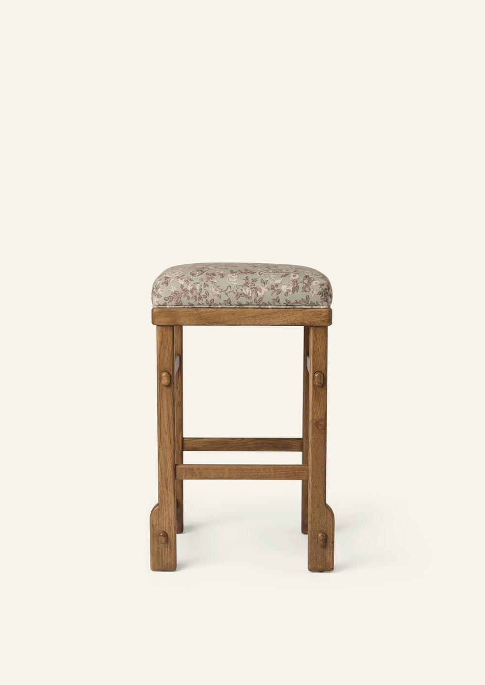 Front view of an upholstered counter stool with a floral-patterned cushion and solid honey oak frame. Clean lines and visible joinery create a versatile design suited for kitchens, islands, and casual dining spaces.