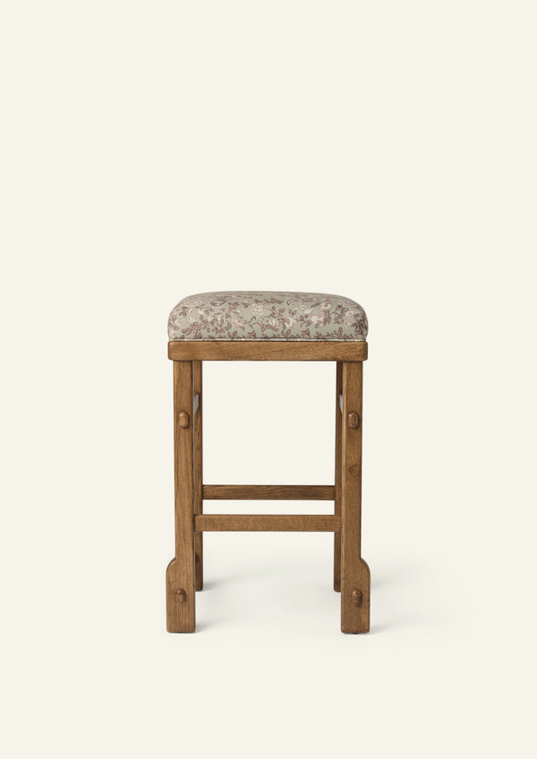 Front view of an upholstered counter stool with a floral-patterned cushion and solid honey oak frame. Clean lines and visible joinery create a versatile design suited for kitchens, islands, and casual dining spaces.