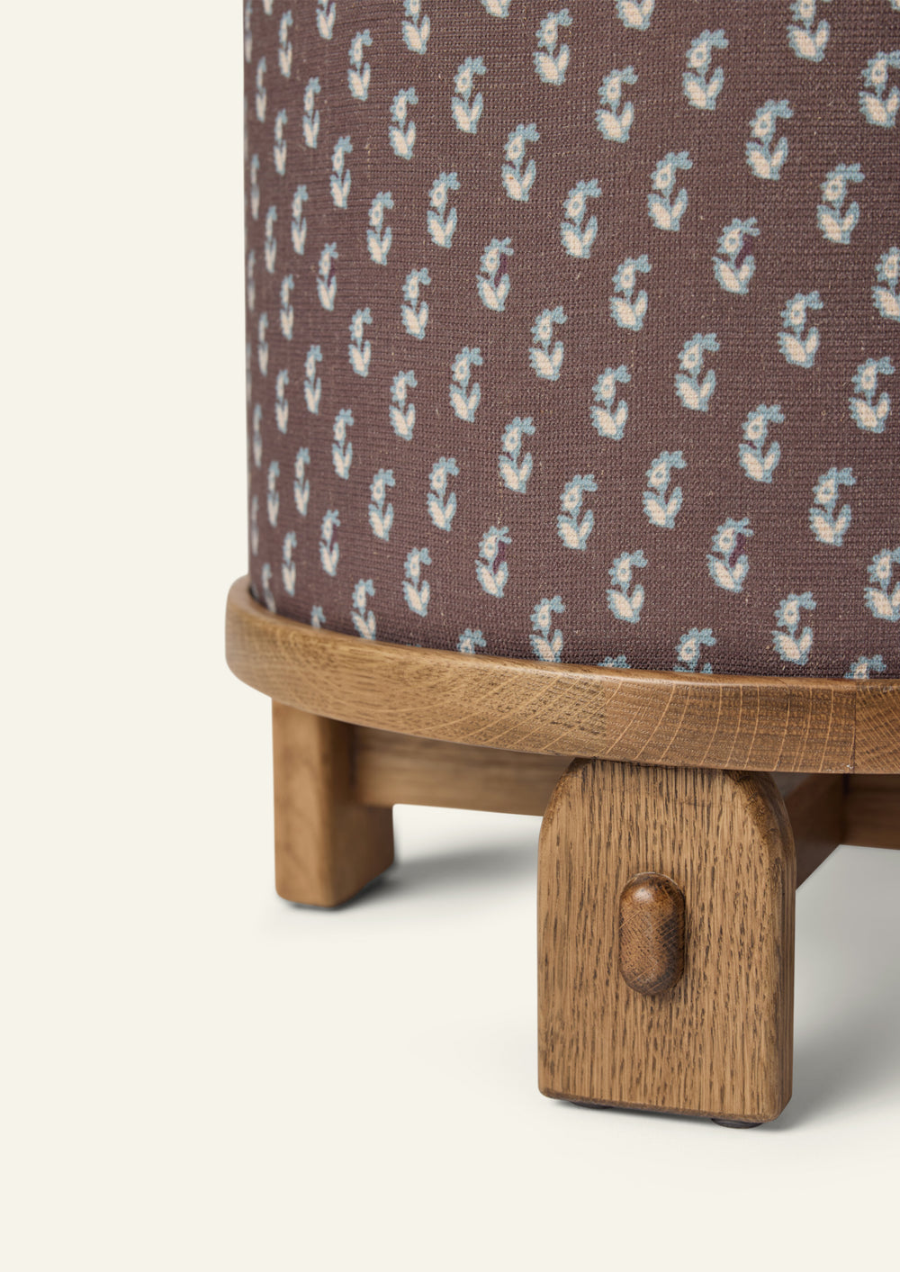 Close-up of the Yara Pouf showing the Cocoa Floral fabric pattern and handcrafted honey oak base. The textured woven upholstery and rounded wood edge highlight the pouf’s artisanal details
