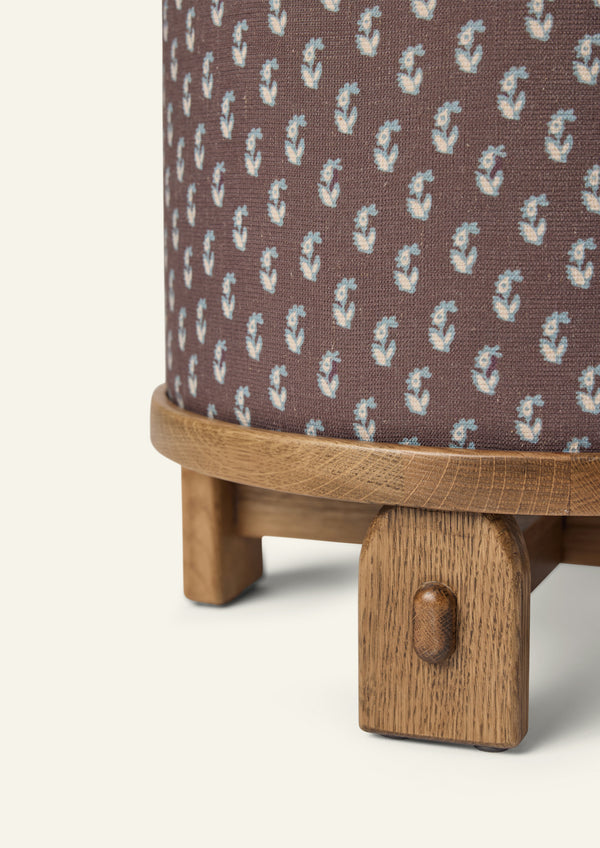 Close-up of the Yara Pouf showing the Cocoa Floral fabric pattern and handcrafted honey oak base. The textured woven upholstery and rounded wood edge highlight the pouf’s artisanal details