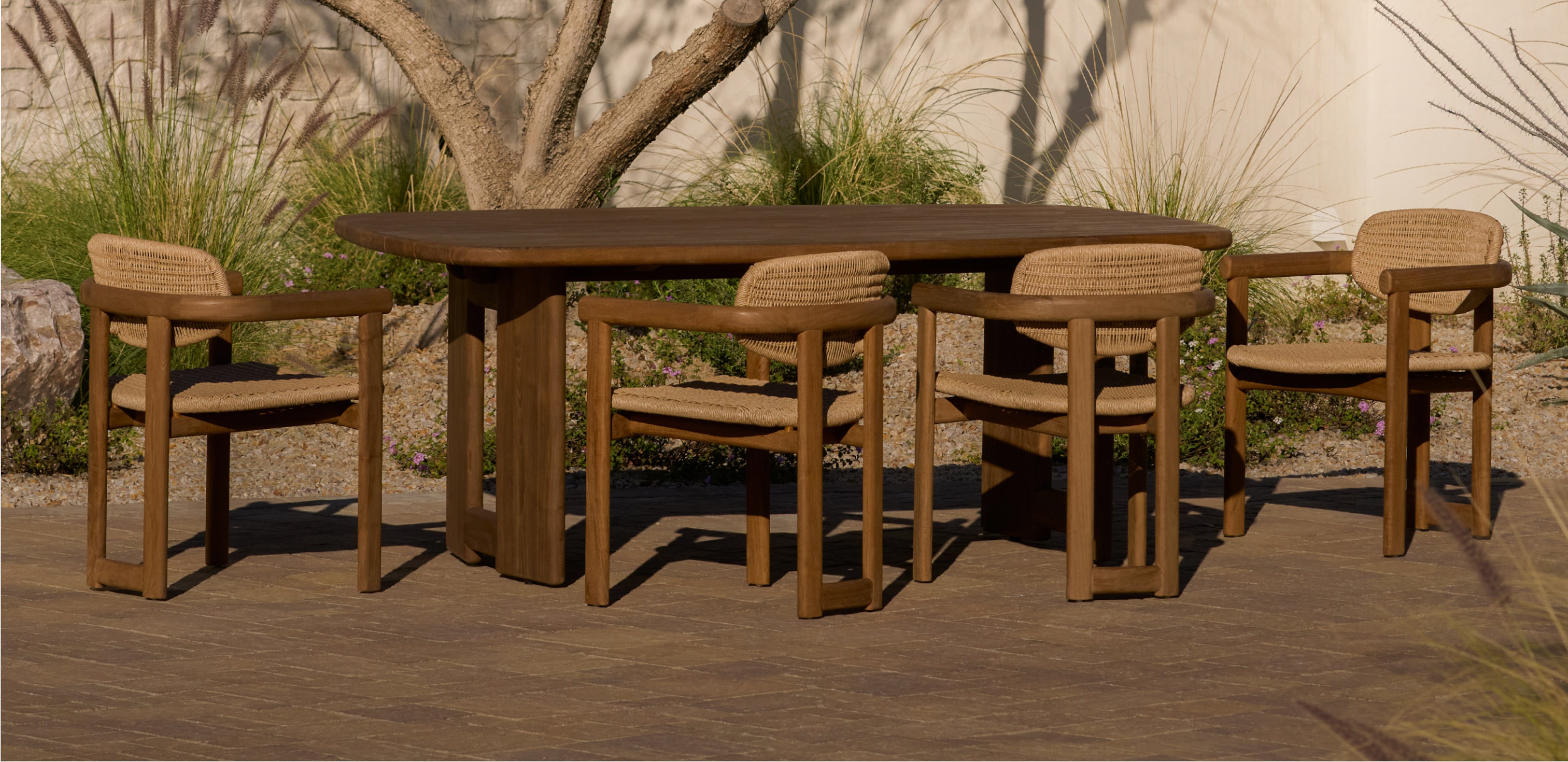 Dark teak outdoor dining set with table and chairs on a patio.