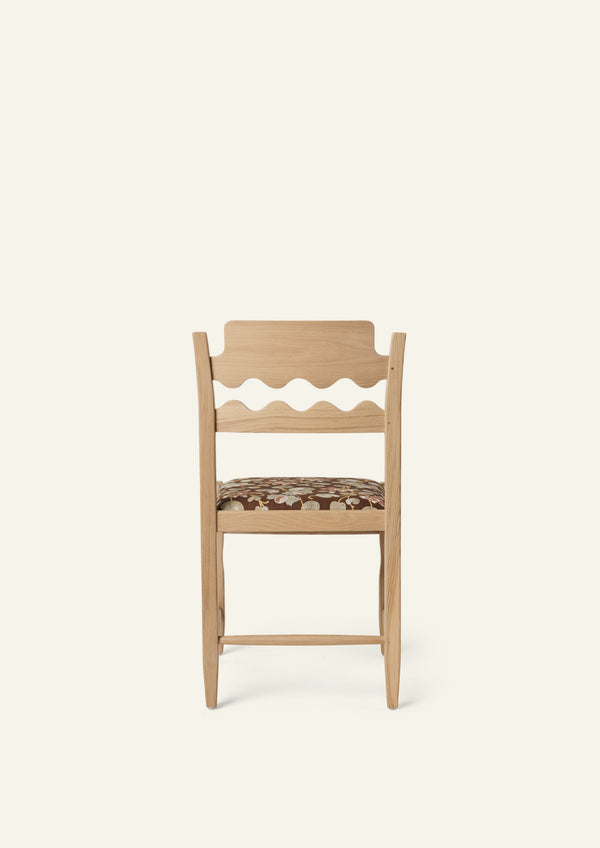 Back view of the Freda Razor Dining Chair in natural oak with an custom fabric seat. The hand-carved scalloped backrest adds a playful yet timeless detail.