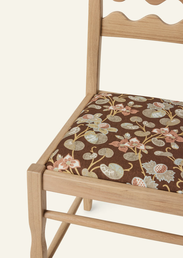 Detailed view of the Freda Razor Dining Chair in natural oak with an custom fabric seat. The hand-carved scalloped backrest adds a playful yet timeless detail.
