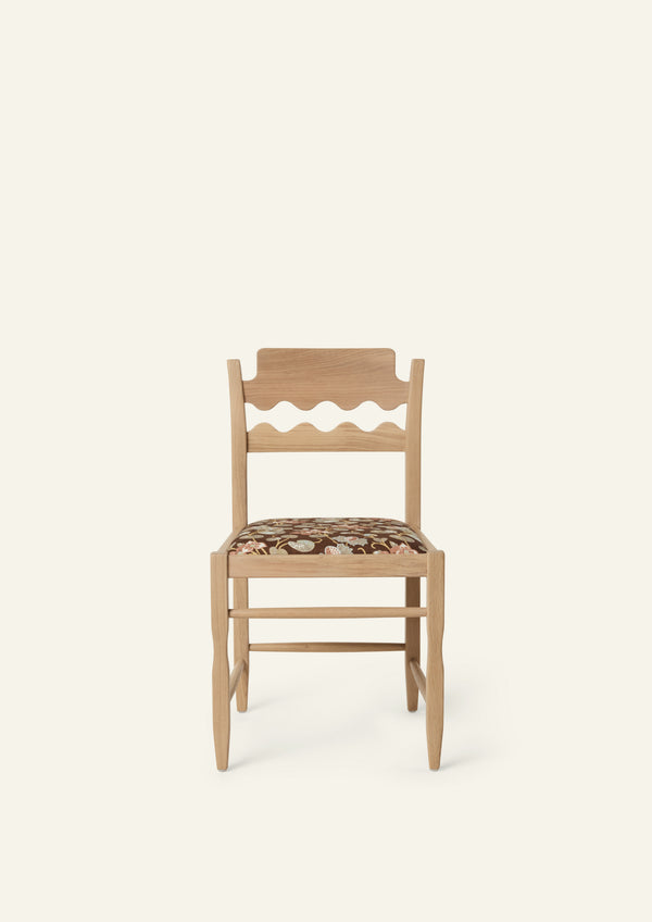 Front view of the Freda Razor Dining Chair in natural oak with an custom fabric seat. The hand-carved scalloped backrest adds a playful yet timeless detail.