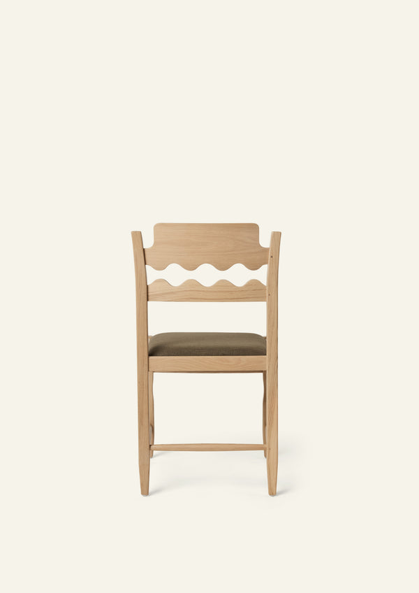 Back view of the Freda Razor Dining Chair in natural oak with an upholstered performance olive linen seat. The hand-carved scalloped backrest adds a playful yet timeless detail.