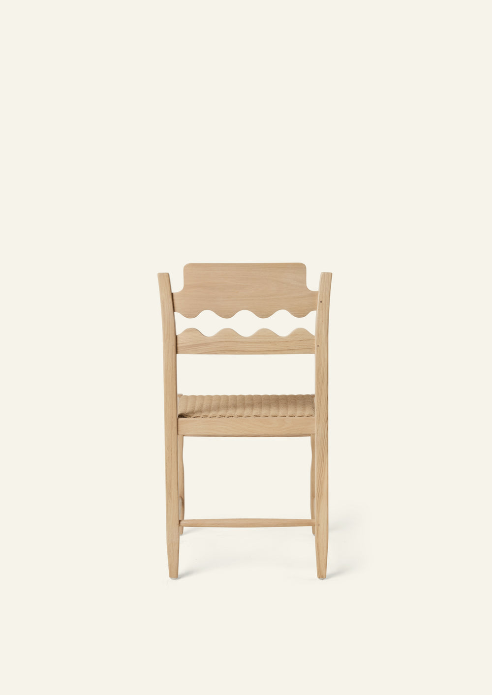 Back view of the Freda Razor Dining Chair in natural oak with a woven paper cord seat. The hand-carved scalloped backrest adds a playful yet timeless detail.