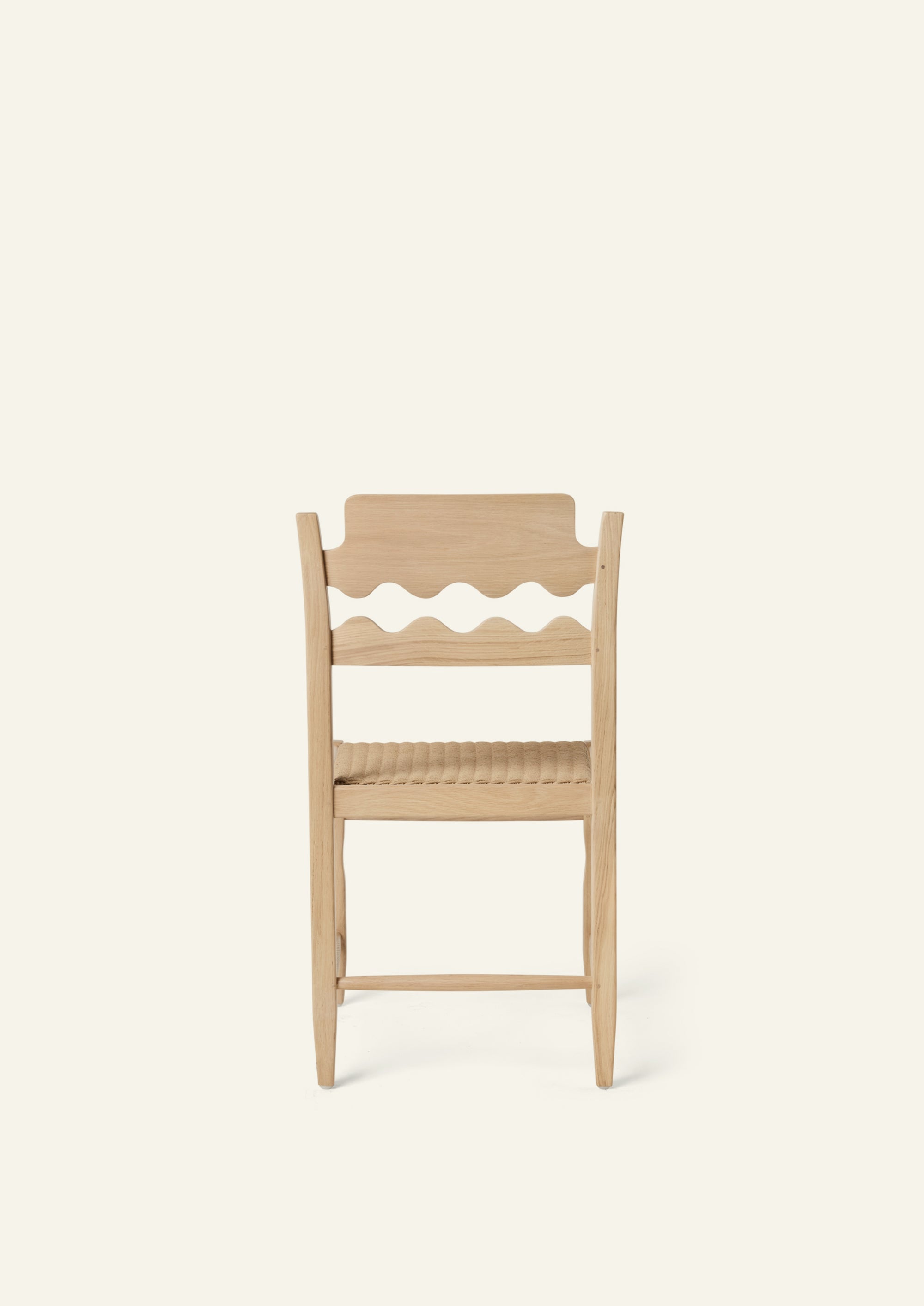 Back view of the Freda Razor Dining Chair in natural oak with a woven paper cord seat. The hand-carved scalloped backrest adds a playful yet timeless detail.