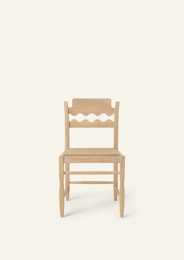 Front view of the Freda Razor Dining Chair in natural oak with a woven paper cord seat. The hand-carved scalloped backrest adds a playful yet timeless detail.