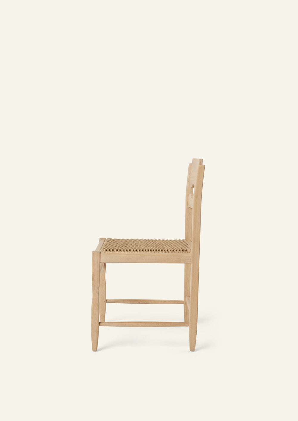 Side view of the Freda Razor Dining Chair in natural oak with a woven paper cord seat. The hand-carved scalloped backrest adds a playful yet timeless detail.