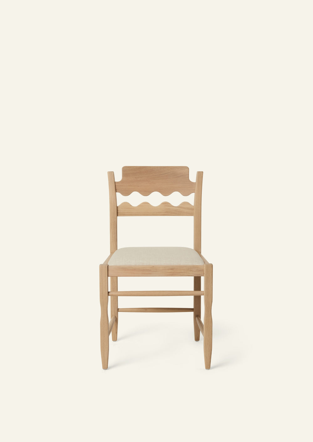 Front view of the Freda Razor Dining Chair in natural oak with an upholstered performance sand linen seat, shown from an angled front view on a neutral background. The hand-carved scalloped backrest adds a playful yet timeless detail.