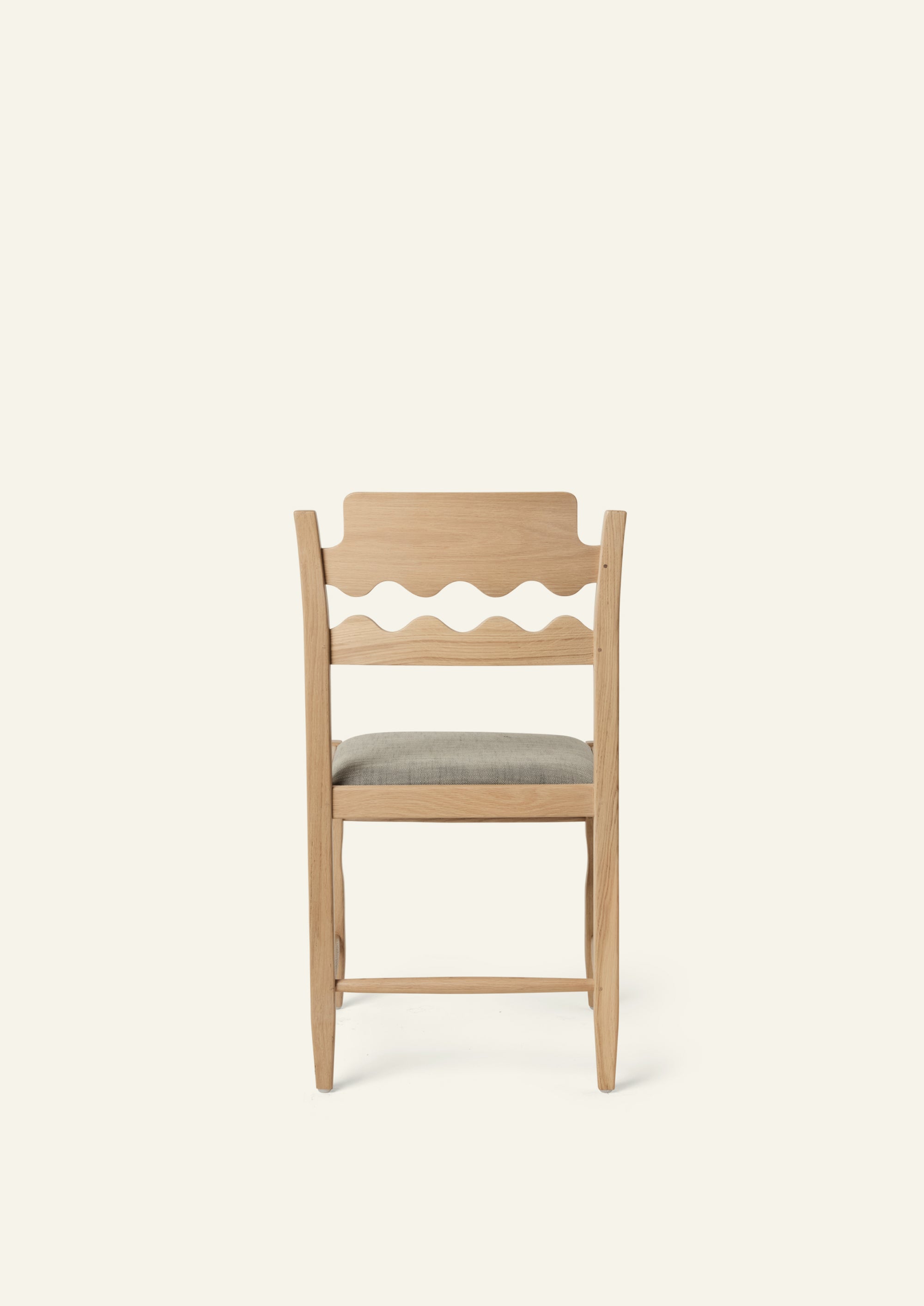 Back view of the Freda Razor Dining Chair in natural oak with an upholstered performance slate linen seat. The hand-carved scalloped backrest adds a playful yet timeless detail.