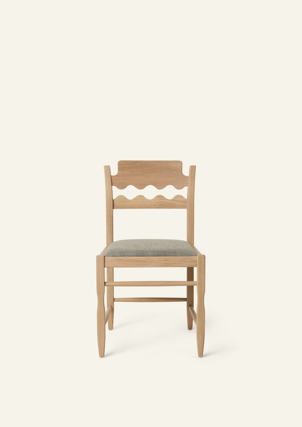 Front view of the Freda Razor Dining Chair in natural oak with an upholstered performance slate linen seat. The hand-carved scalloped backrest adds a playful yet timeless detail.