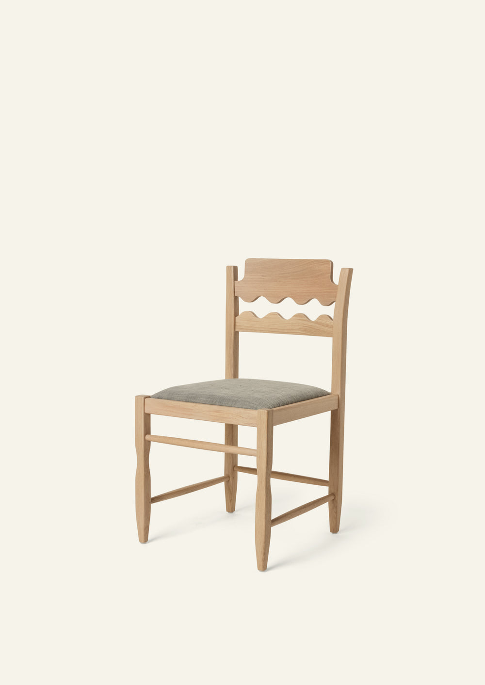 Freda Razor Dining Chair in natural oak with an upholstered performance slate linen seat, shown from an angled front view on a neutral background. The hand-carved scalloped backrest adds a playful yet timeless detail.