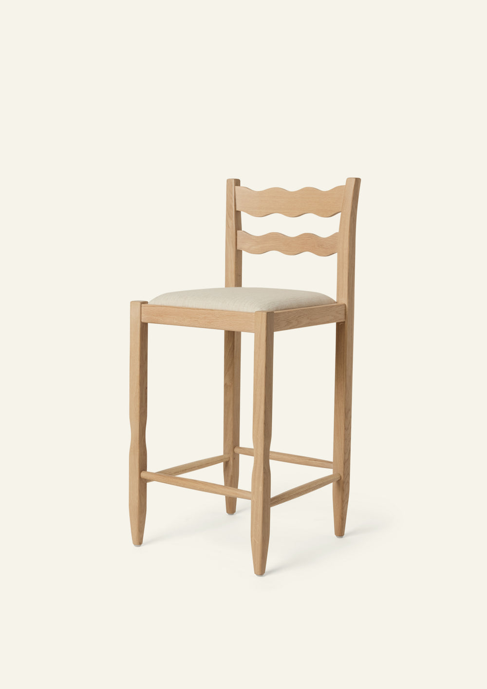Freda Wave Counter Stool in natural oak with an upholstered performance sand linen seat, shown from an angled front view on a neutral background. The chair features Freda’s signature double-wave backrest with softly sculpted, hand-carved detailing.