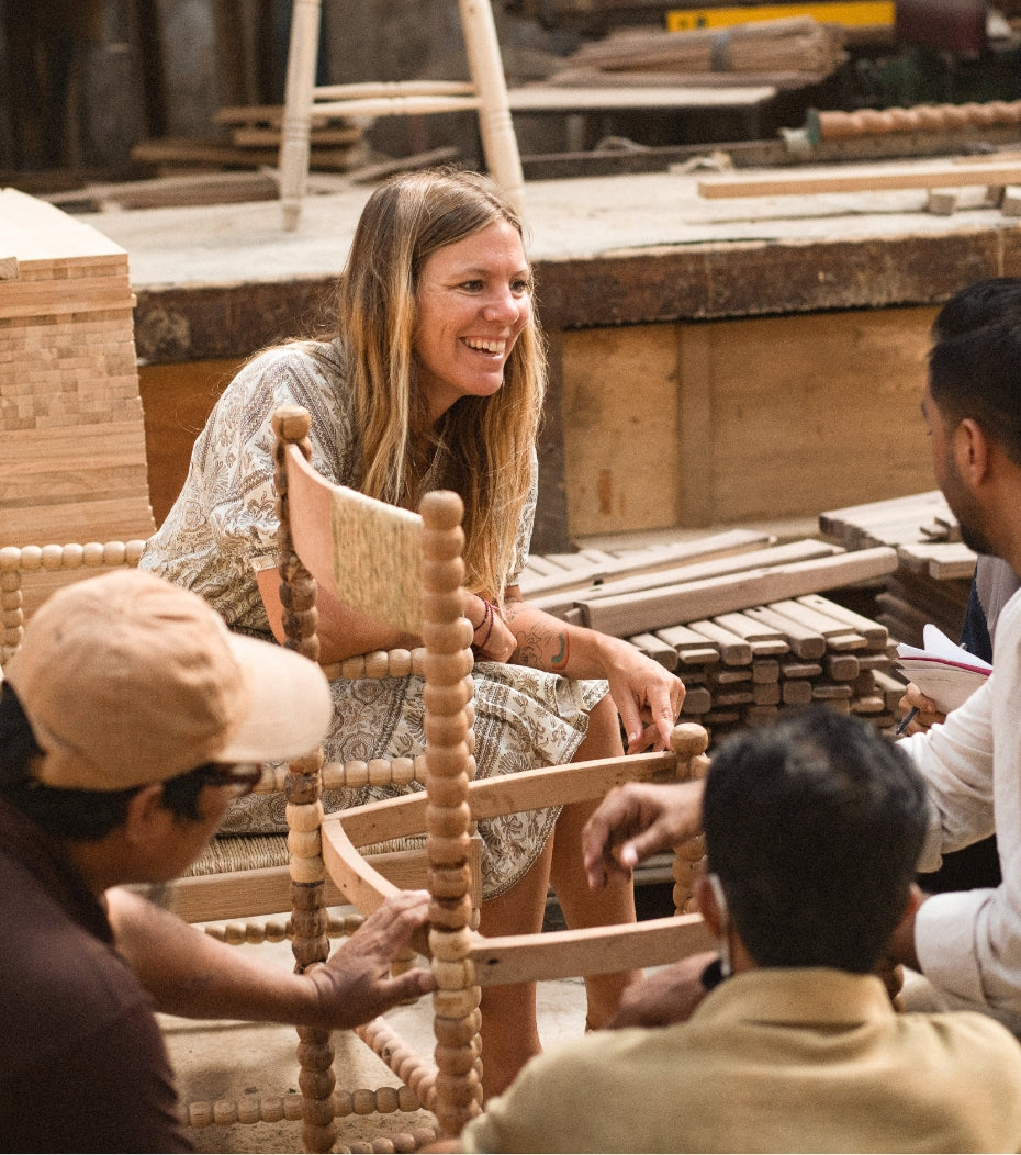 woman in a factory watching a chair being hand carved.