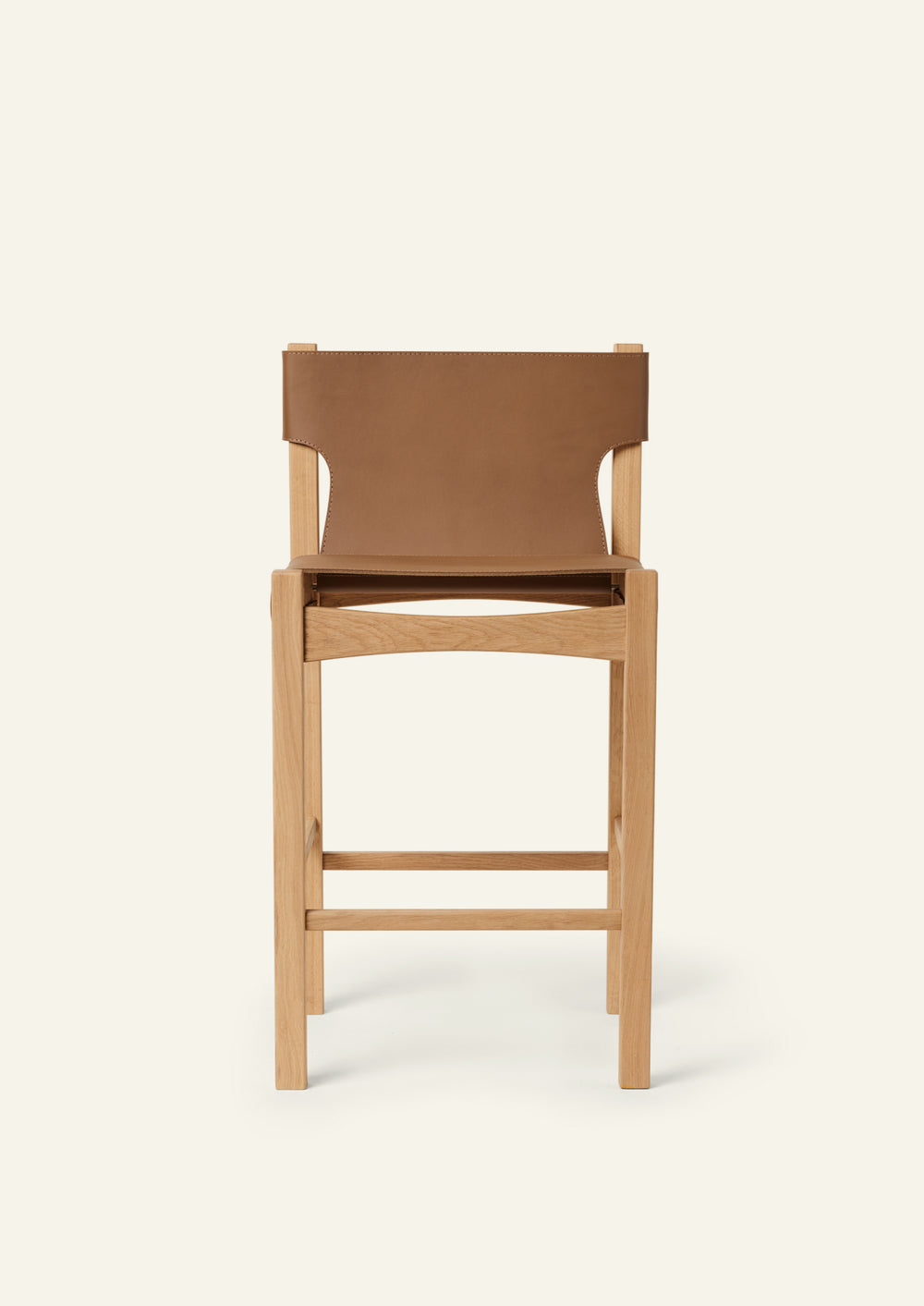 Front view of the counter stool highlighting the vegetable-tanned leather seat and backrest framed by solid white oak. Clean lines and balanced proportions create a timeless, versatile design.
