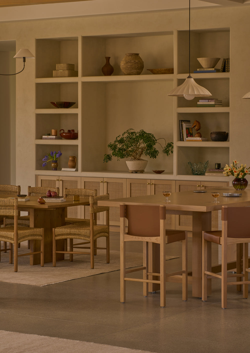 Henrik Counter Stools gathered around a large white oak island table in a warm, inviting interior. The combination of natural oak and rich leather creates a sophisticated setting for dining and entertaining.