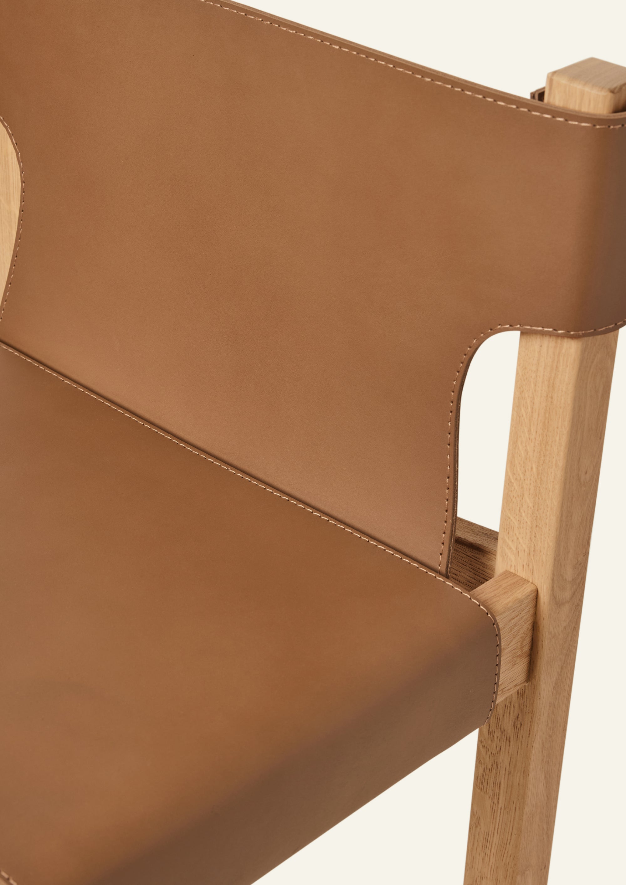 Close-up of the chair’s vegetable-tanned full-grain cognac leather seat and backrest, highlighting the smooth surface, tailored stitching, and the natural character of the hide.