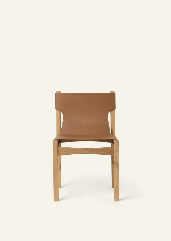 Front view of the dining chair featuring a full-grain leather sling seat and backrest framed by solid white oak. The balanced proportions and clean geometry create a timeless dining silhouette.