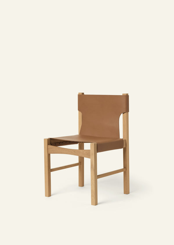 Three-quarter view of the Henrik Dining Chair featuring a solid white oak frame and suspended full-grain leather seat and backrest. The clean-lined silhouette combines traditional craftsmanship with a refined, contemporary profile.
